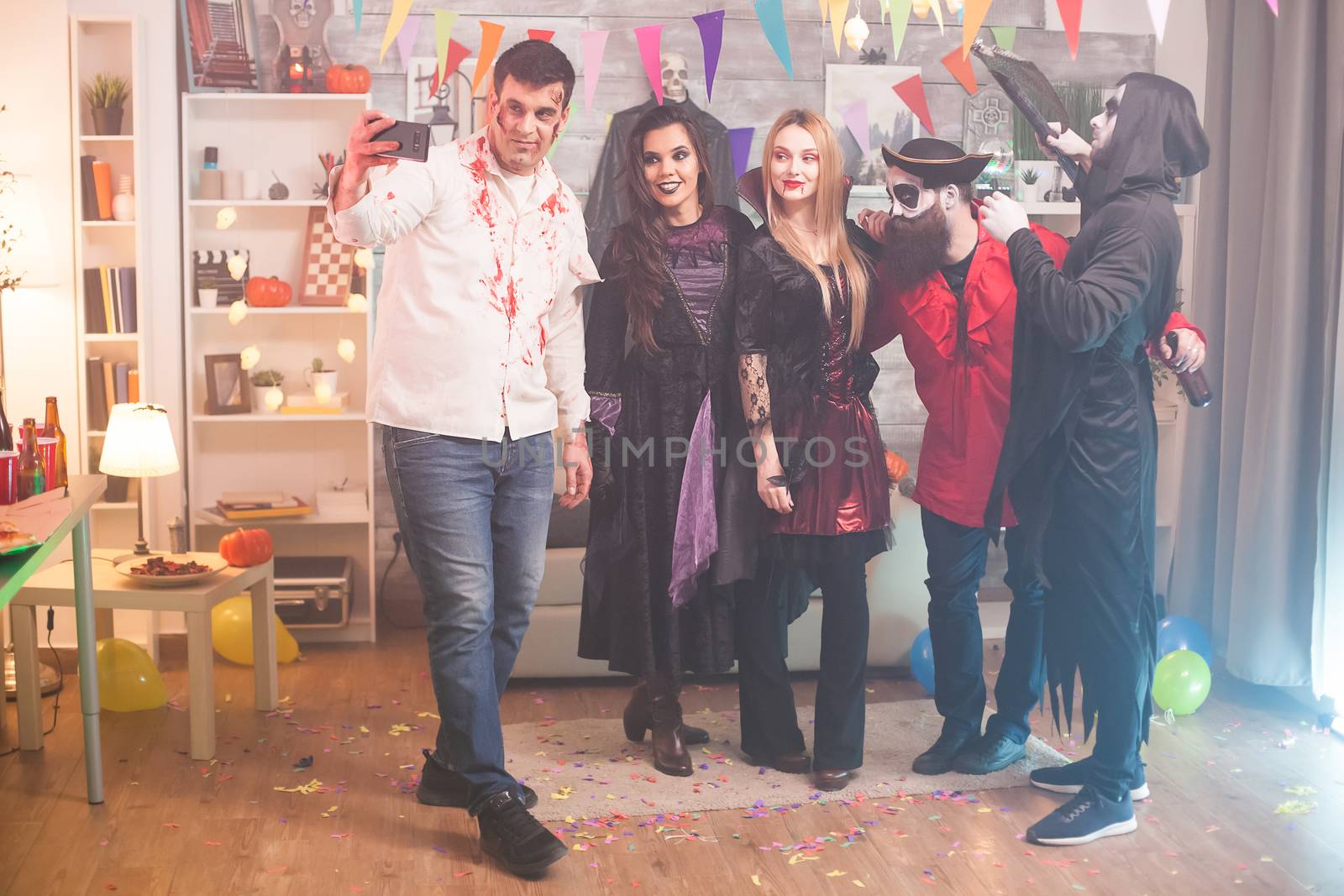 Spooky man taking a selfie with his friends at halloween party.