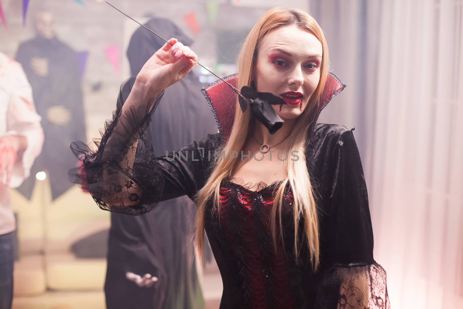 Young woman dressed up like a creepy vampire with group of people celebrating halloween.
