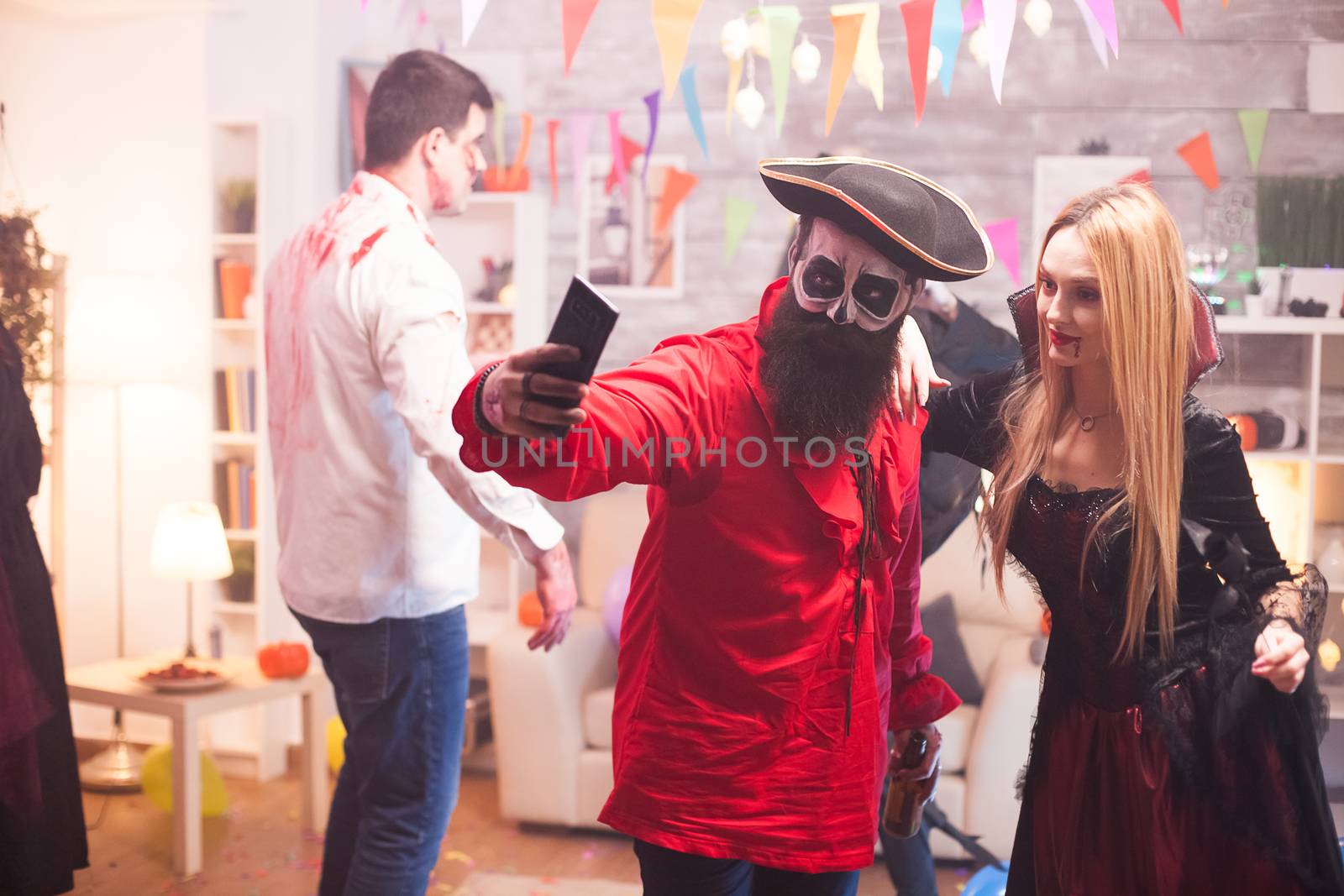 Couple dressed up like a pirate and vampire taking a selfie at halloween party.