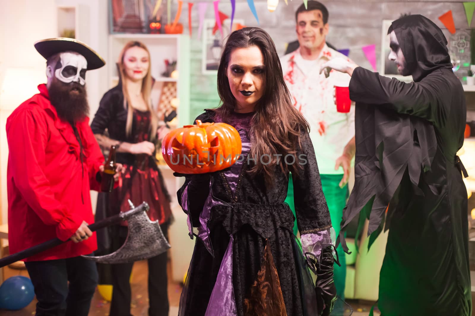 Witch holding a pumpkin and looking at the camera by DCStudio