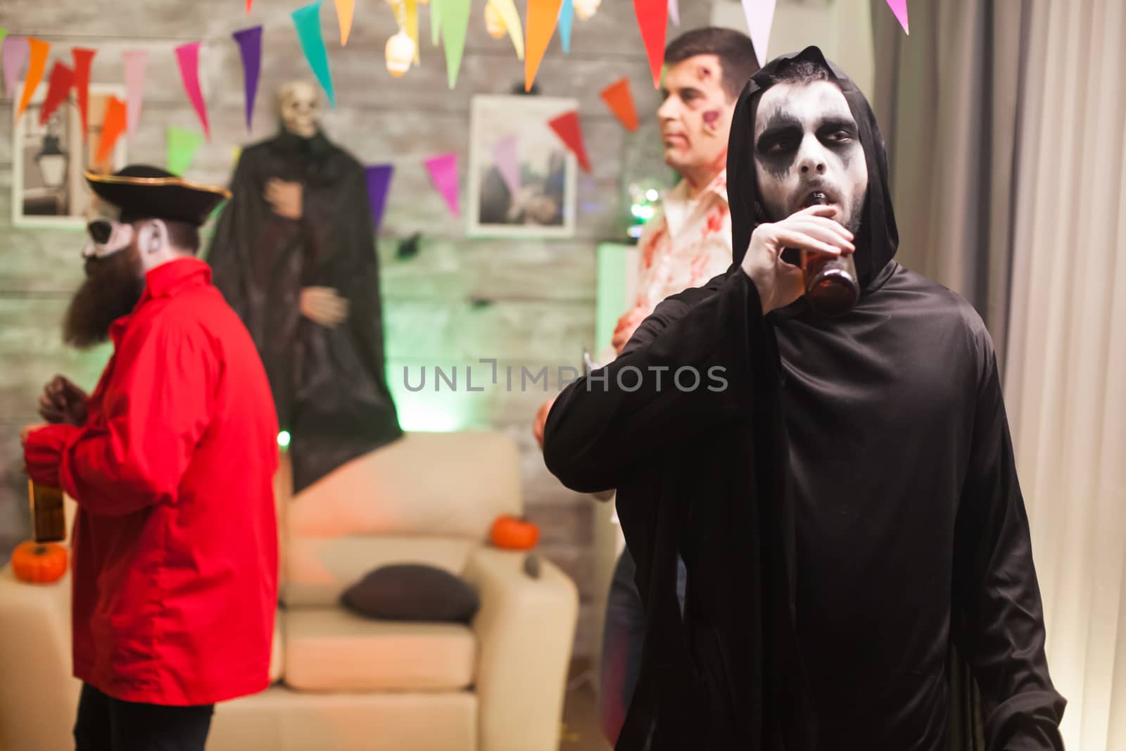 Grim reaper enjoying his beer at halloween celebration by DCStudio