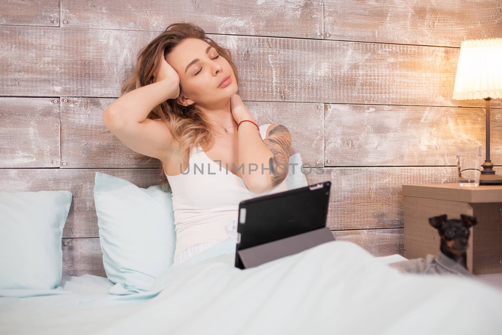 Tired beautiful woman in pajamas while working on tablet computer by DCStudio