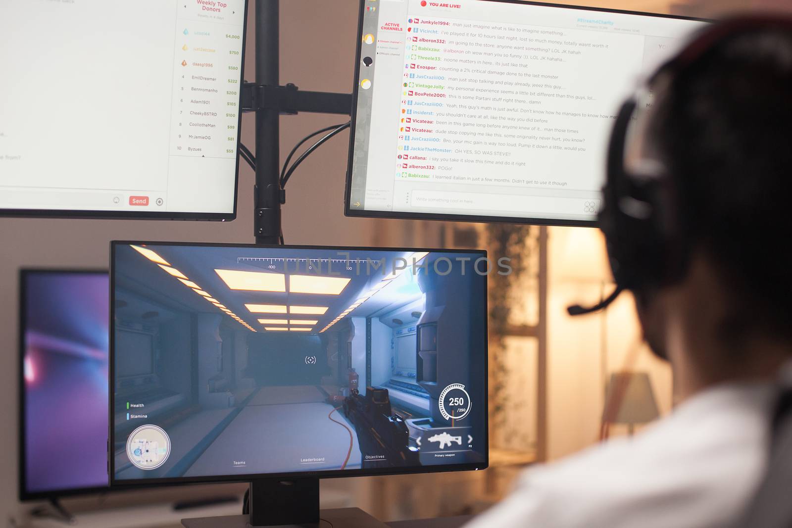 Over shoulder shot of man playing shooter game on computer. Multiple monitors.