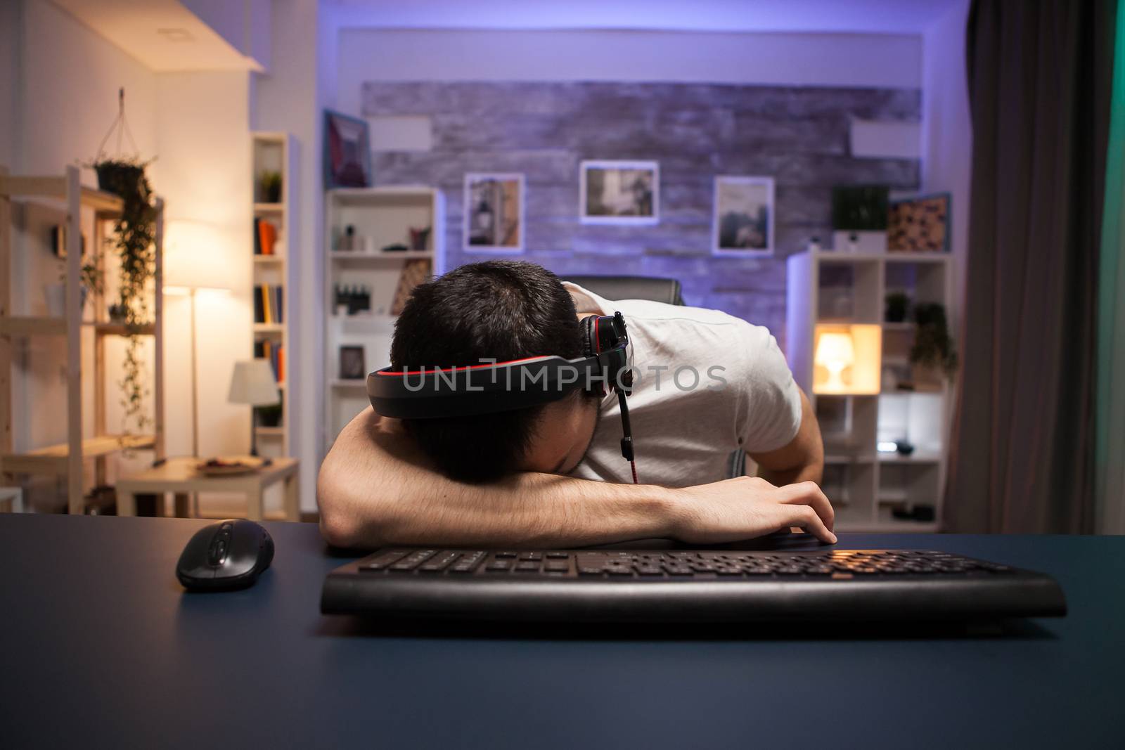 Pov of young man keeping his head on the office after losing and shooter game on stream.