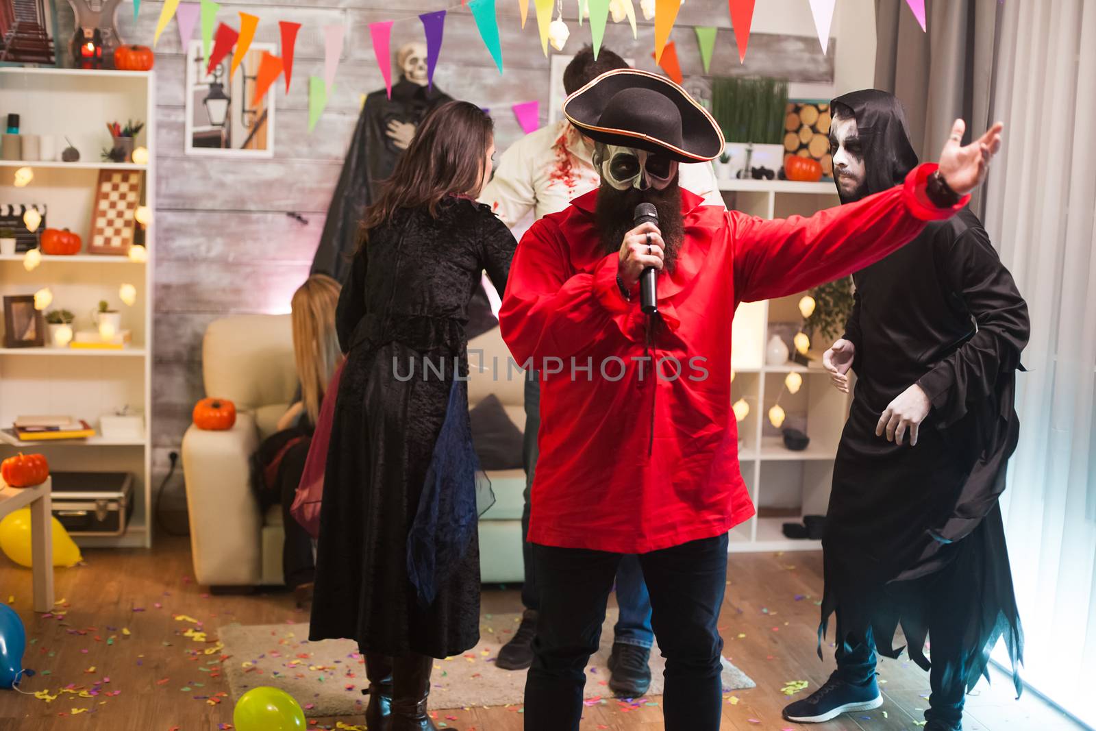 Attractive man dressed up like a pirate doing karaoke at halloween party with his friends.