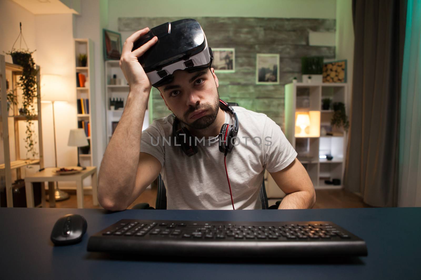 Pov of young man taking off his virtual reality goggles after losing at online games.