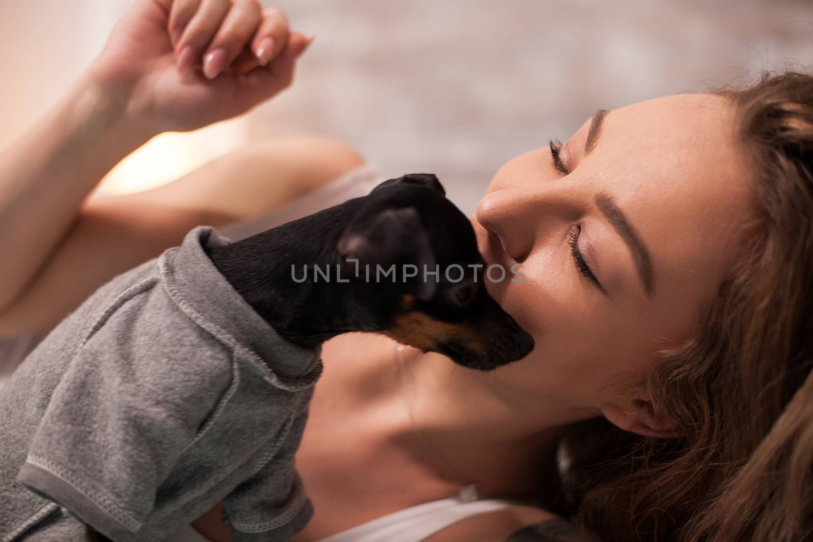 Pretty caucasian woman wearing pajamaslaying in bed with her little dog at night.