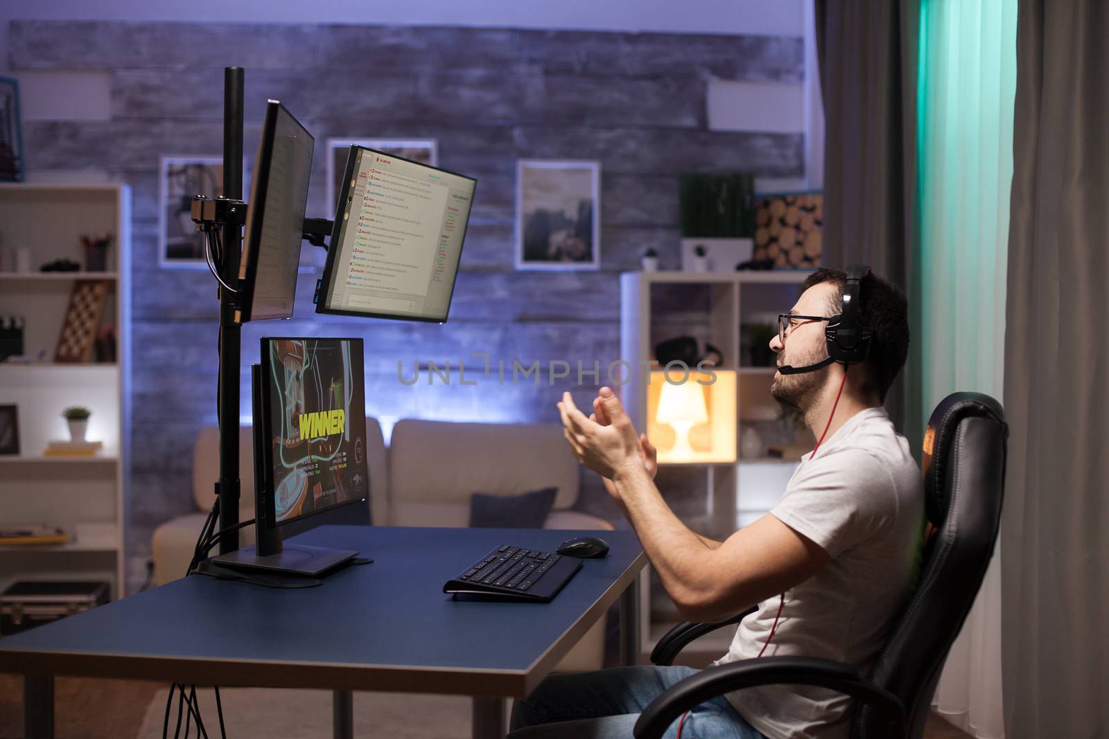 Side view of professional shooter gamer clapping after his victory on an important online competition.