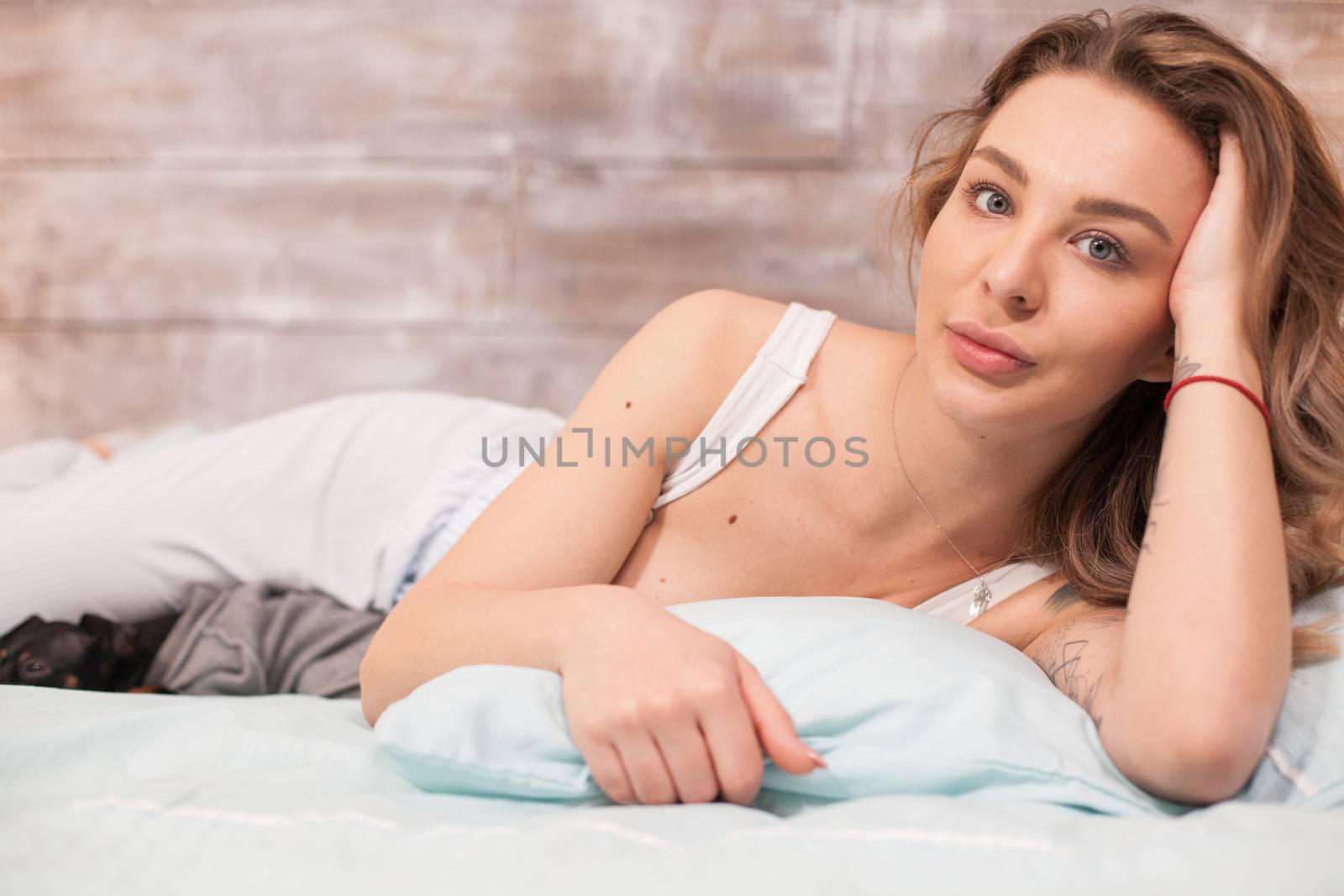 Attractive young wearing pajamas in bed at night by DCStudio