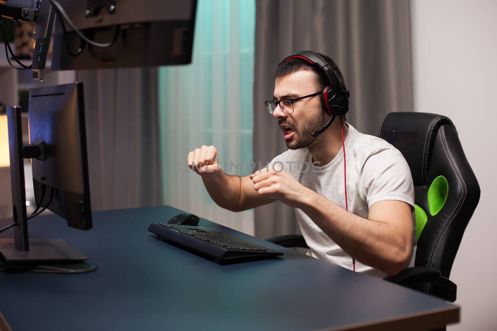 Young man with headphones yelling after his victory at online shooter game.