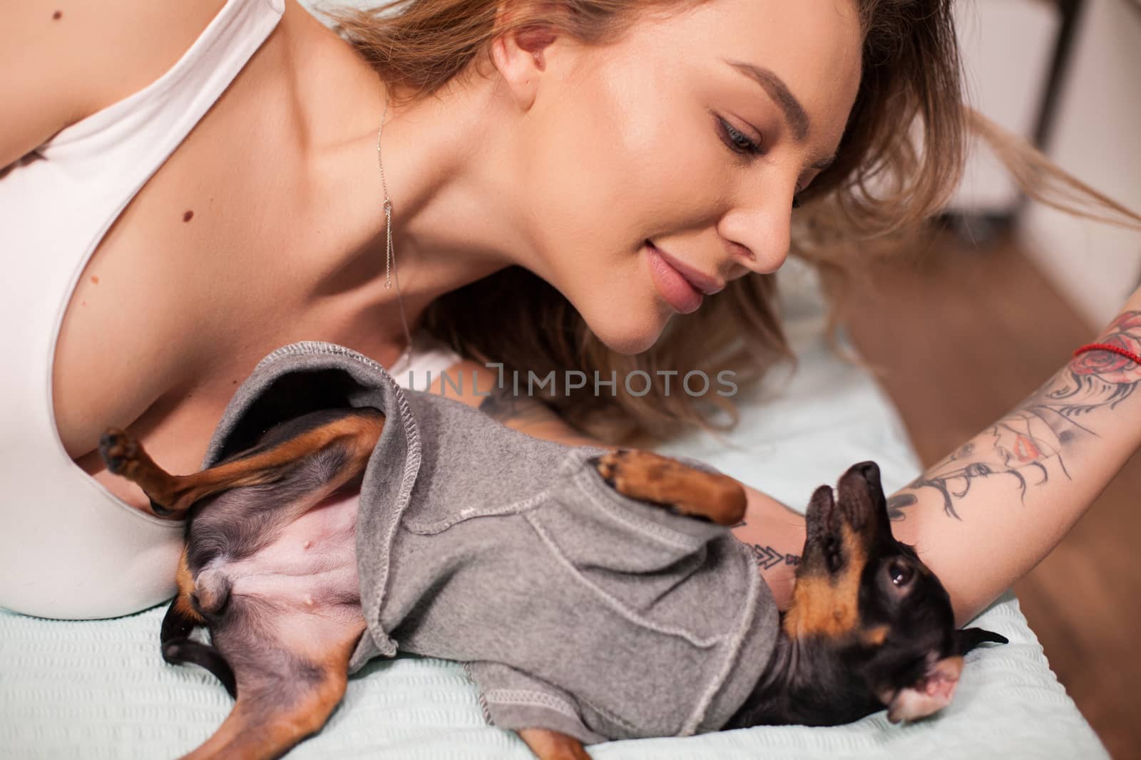 Cheerful woman and her pet playing in bed at night. Woman in pajamas