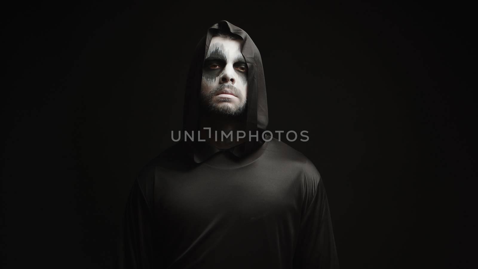 Young man dressed up like grim reaper over black background in halloween theme decoration