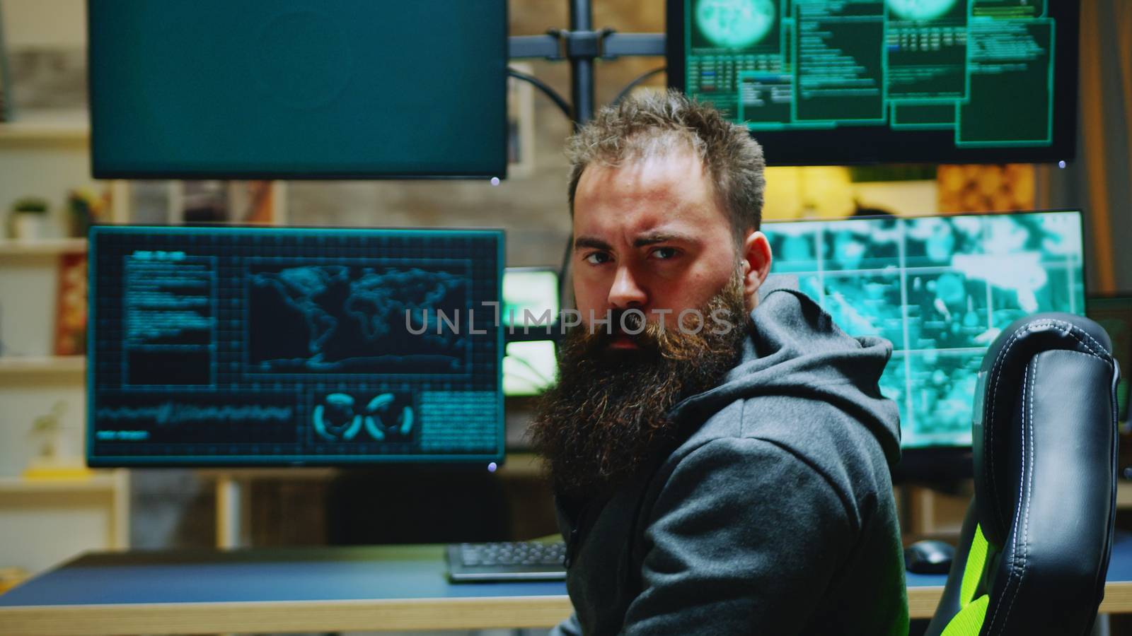 Bearded hacker turning and looking into the camera while breaking a firewall.