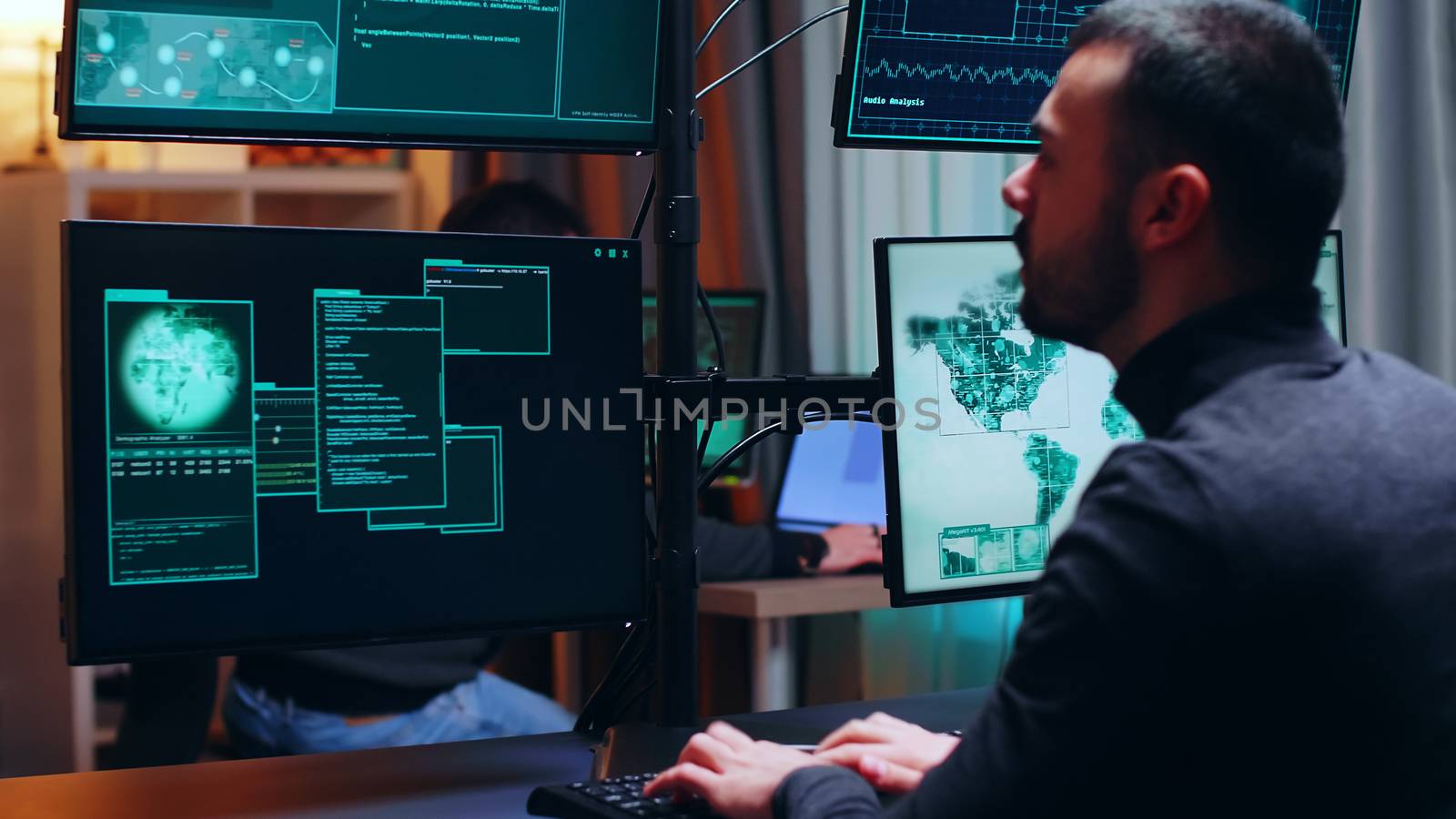 Dangerous hacker watching multiple monitors while working. Cyber criminal.
