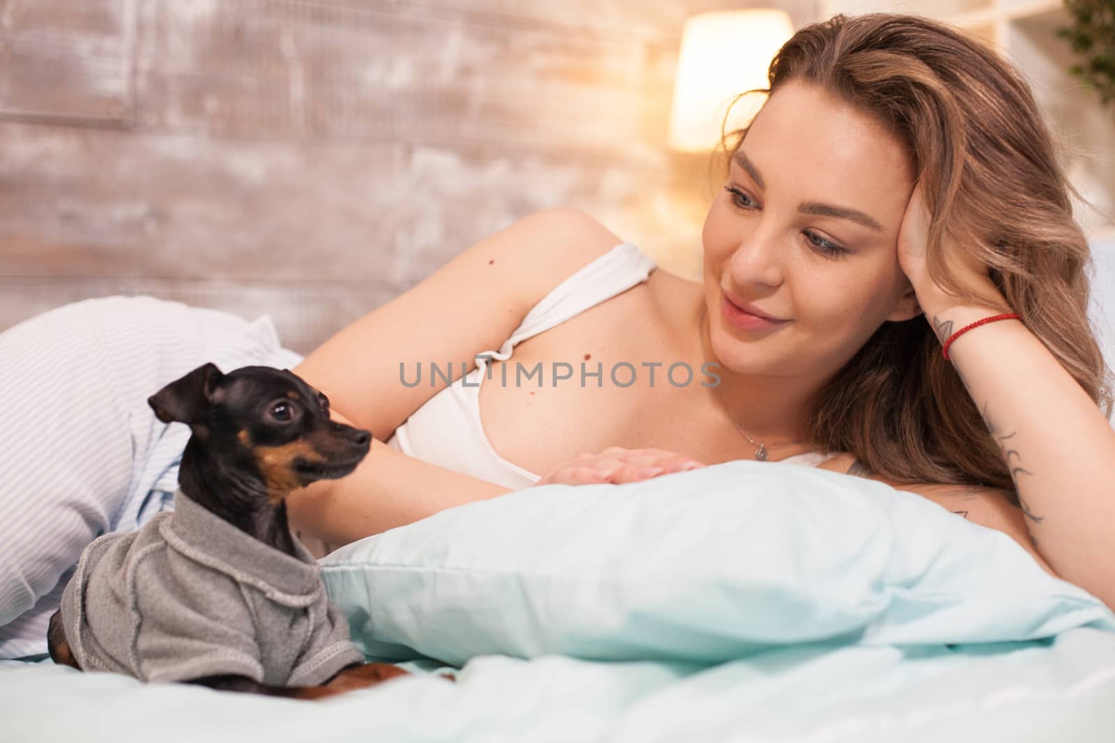 Young woman in pajamas sitting comfortably in bed by DCStudio