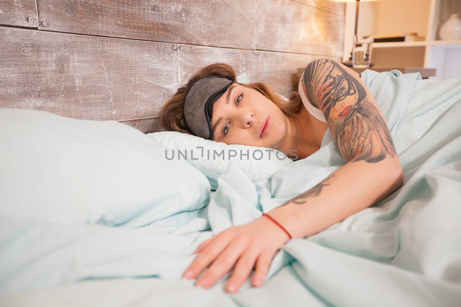Sleepy beautiful young woman with tattoo with cover mask.