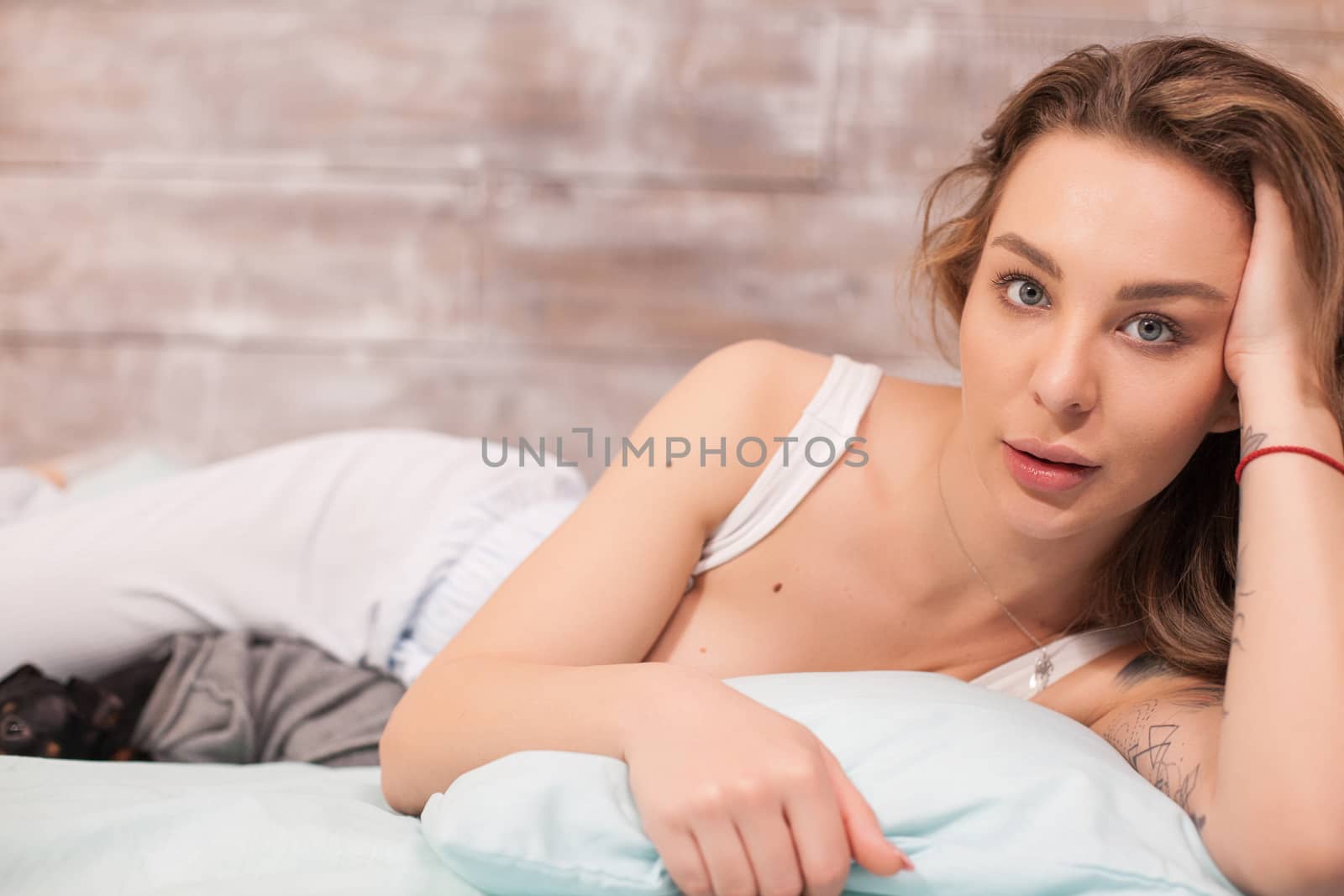 Portrait of beautiful woman in pajamas looking at the camera while her dog is resting.