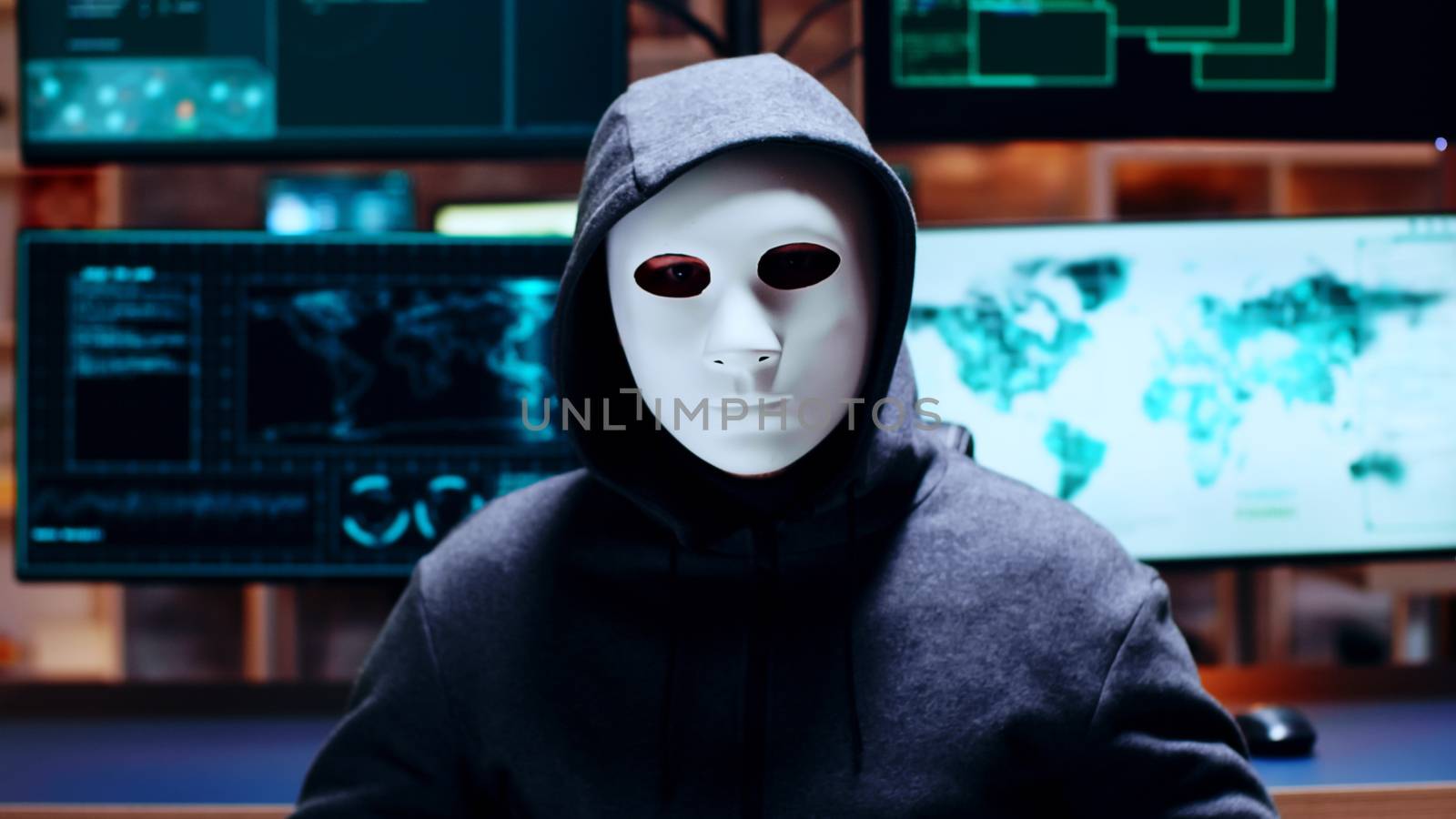 Zoom in shot cyber criminal wearing a white mask looking at the camera.