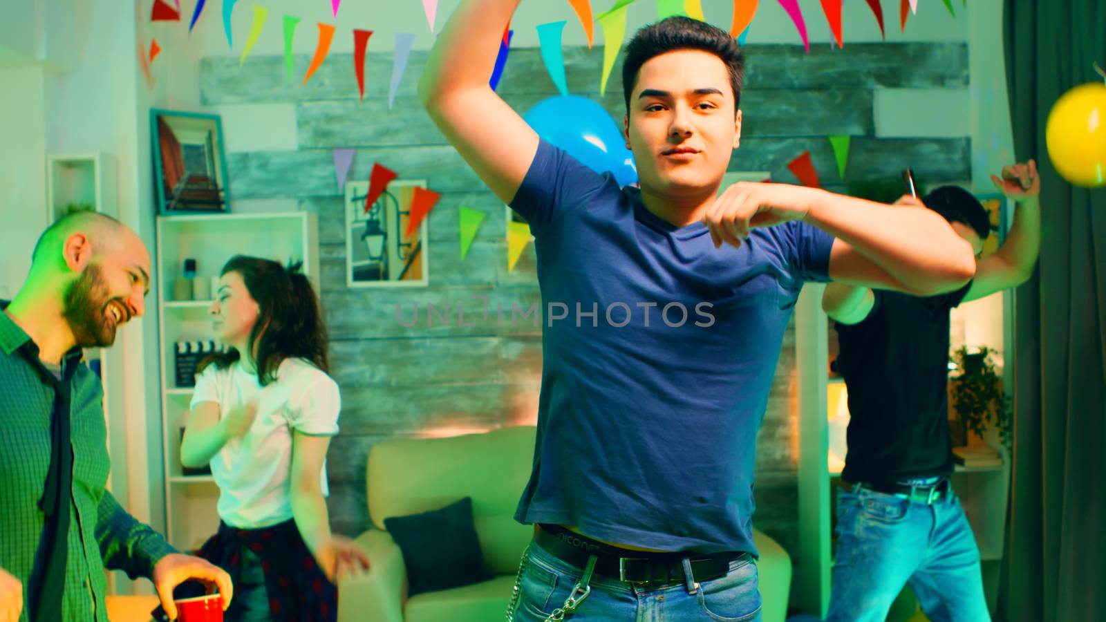 Excited young man partying with his friends. Attractive group of people dancing in the background