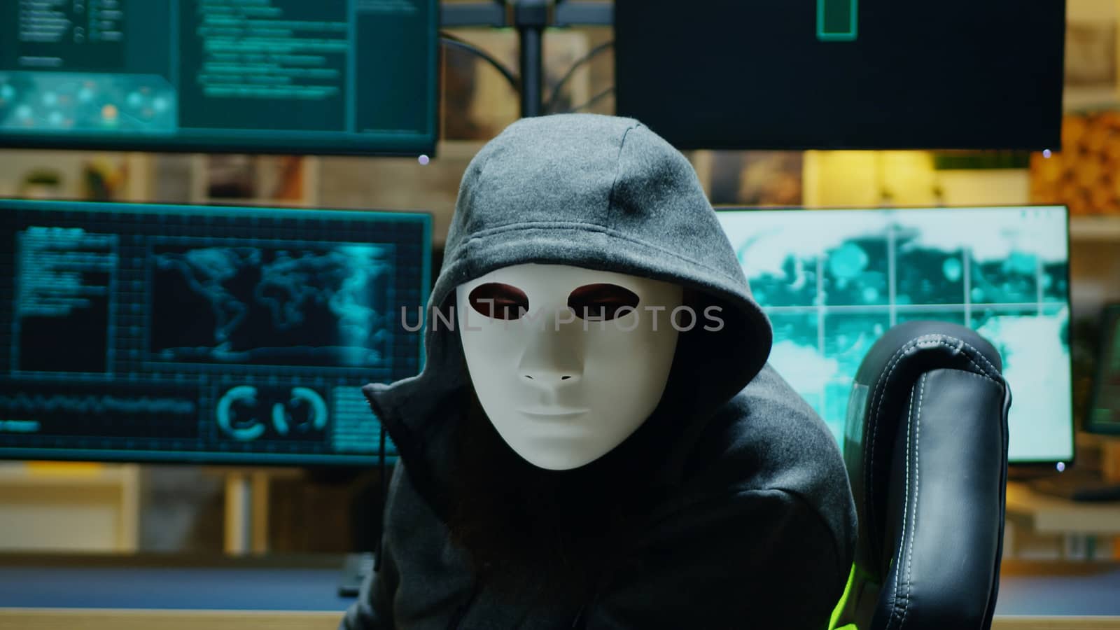 Masked hacker in his apartment looking into the camera by DCStudio