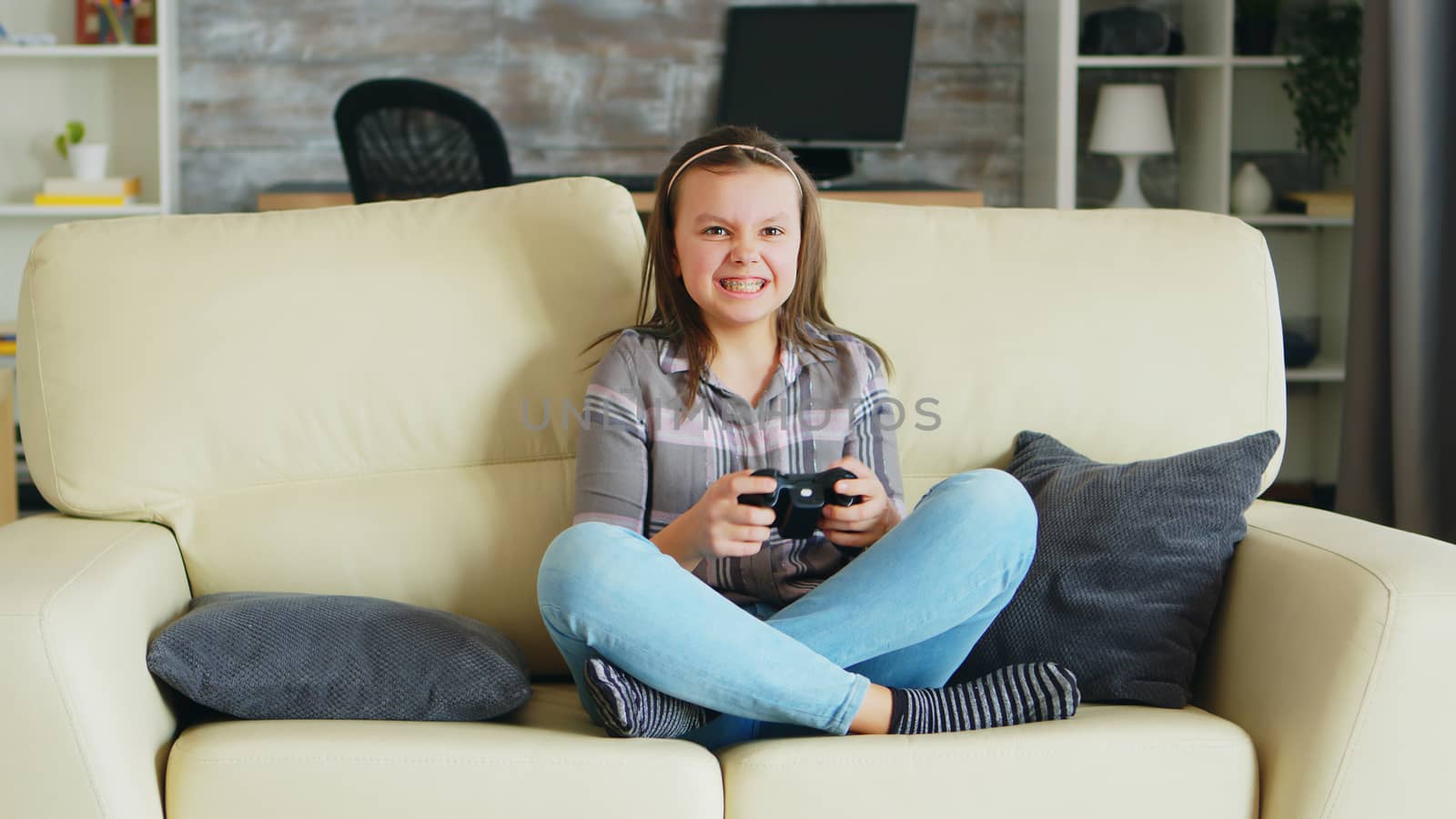 Cheerful little girl playing video games using wireless controller by DCStudio