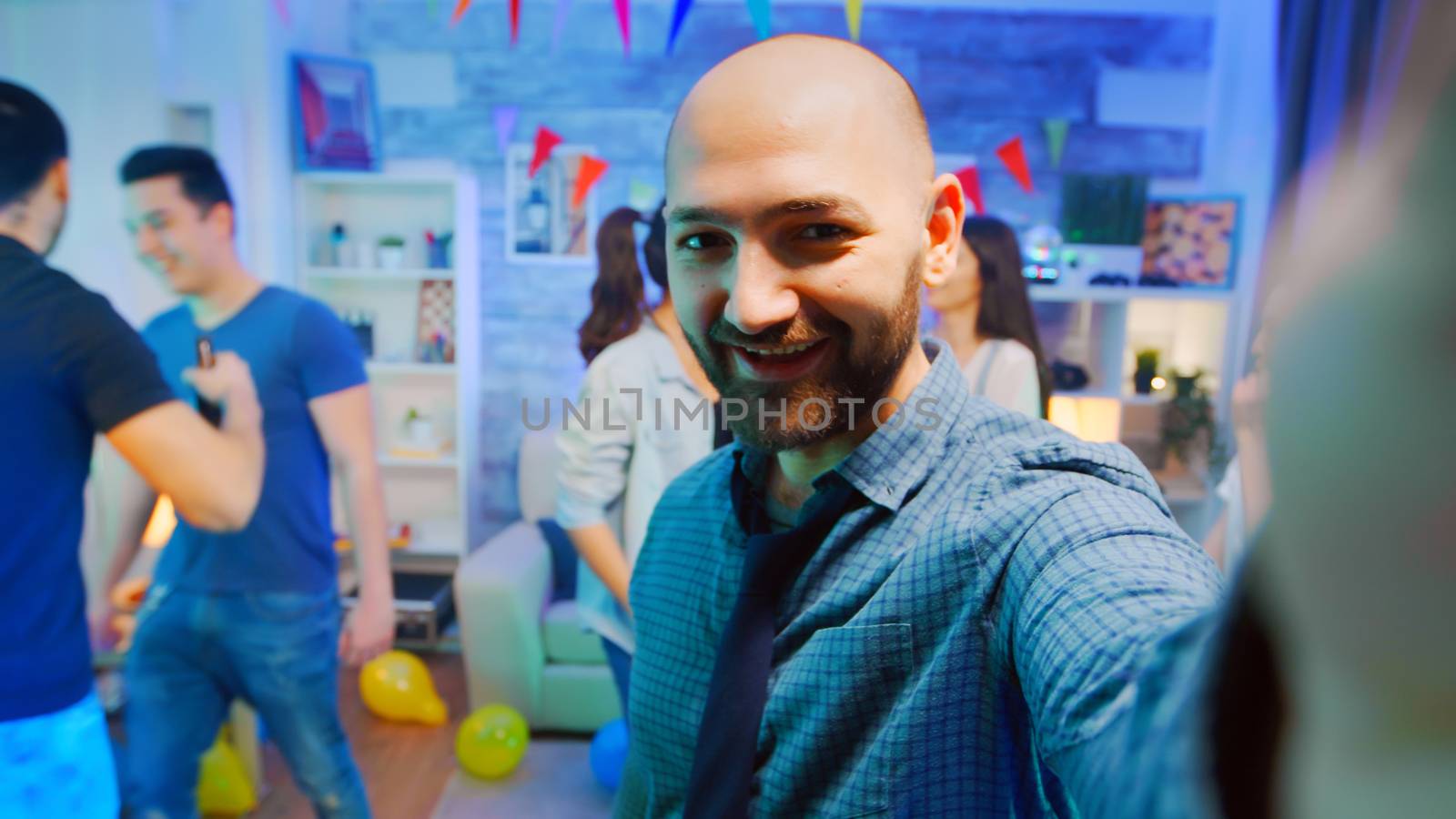 Pov of attractive bald man waving at the camera while partying with his friends