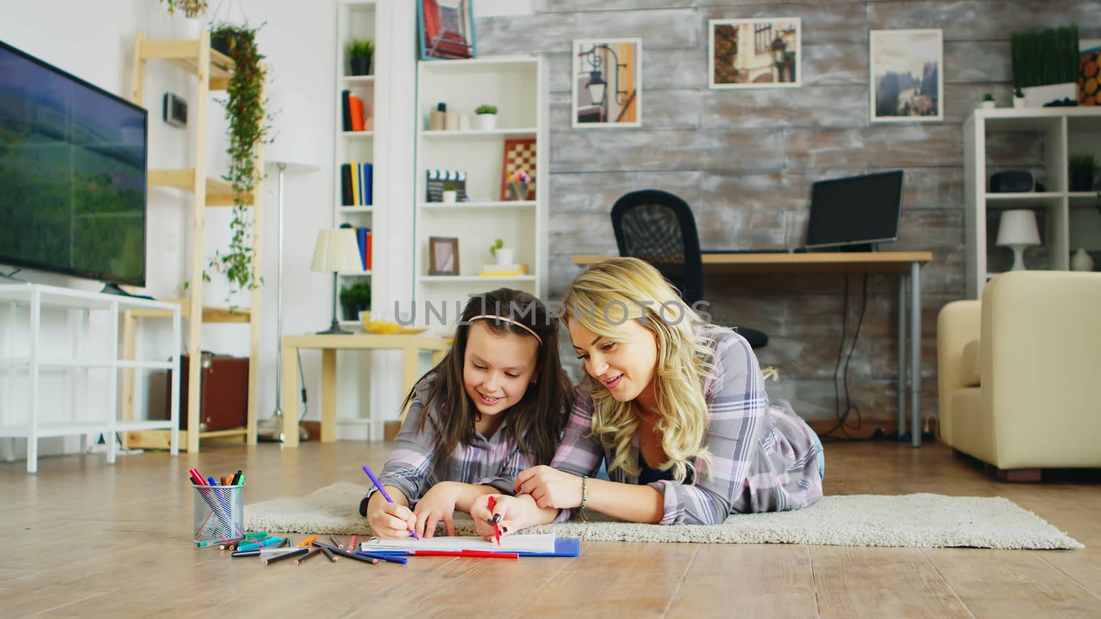 Beautiful young mother teaching her little daughter to draw.