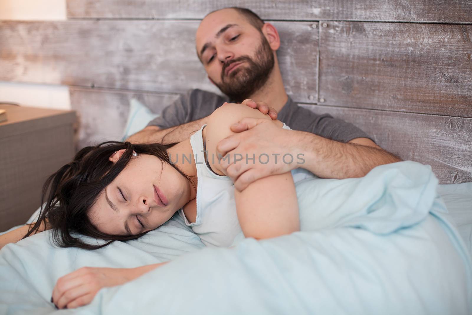 Beautiful wife in pajamas sleeping on her husband lap in the morning.