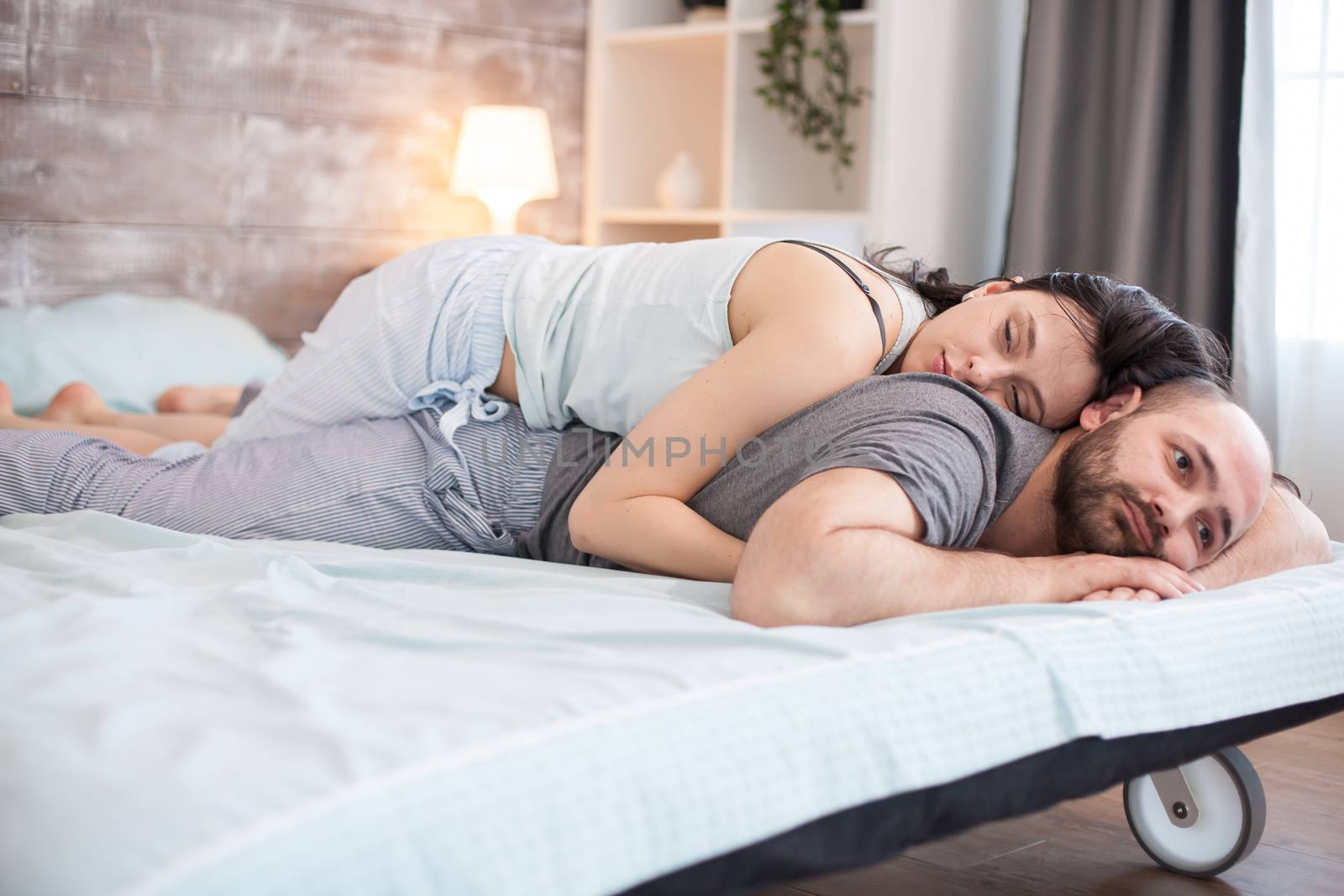 Romantic caucasian couple laying in bed by DCStudio