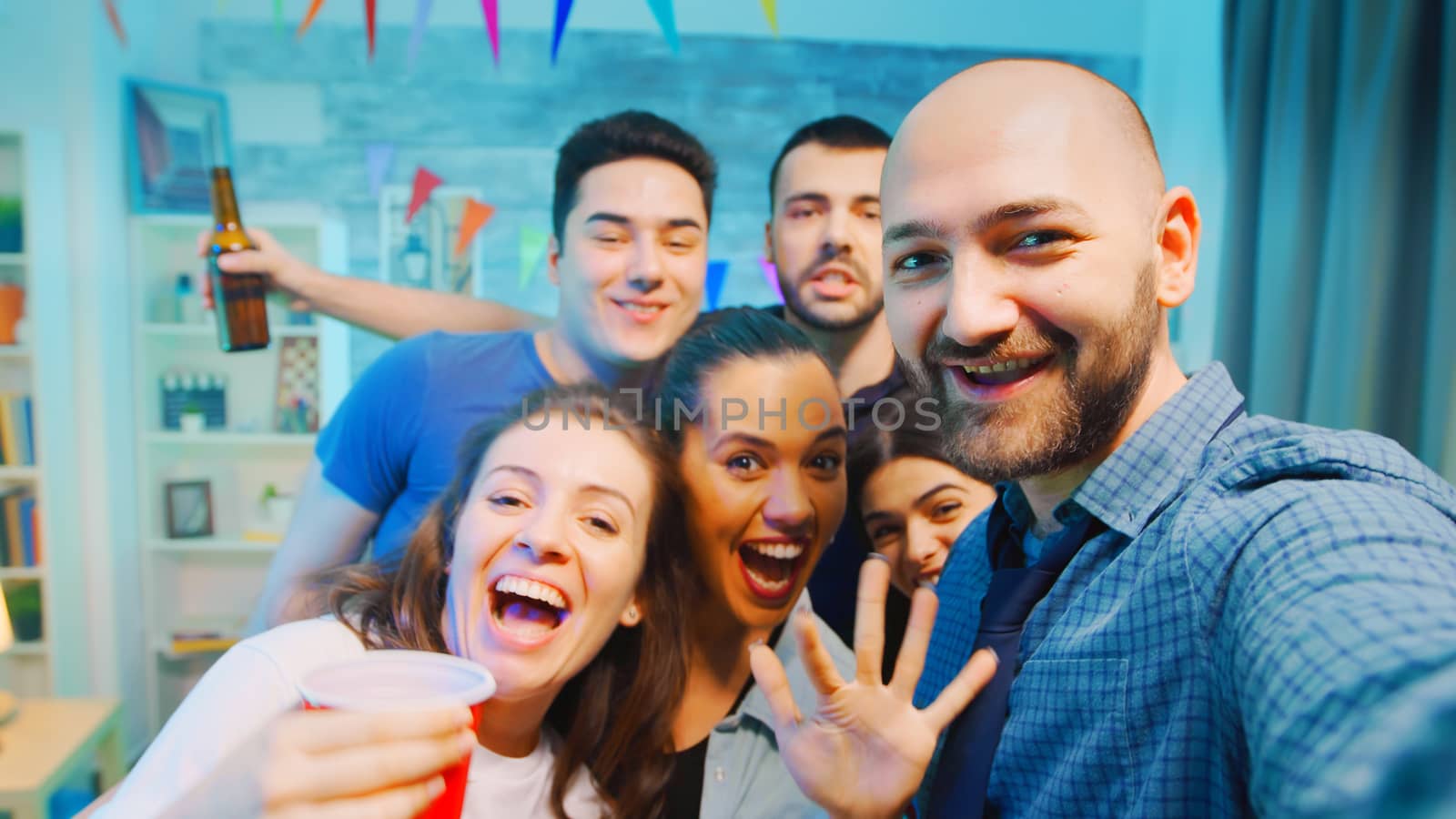 Pov of cheerful young man in a room partying with his friends and inviting people to come over.