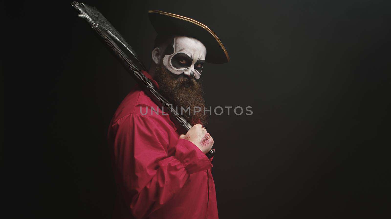 Crazy man with make up dressed up like pirate with an axe for halloween party.