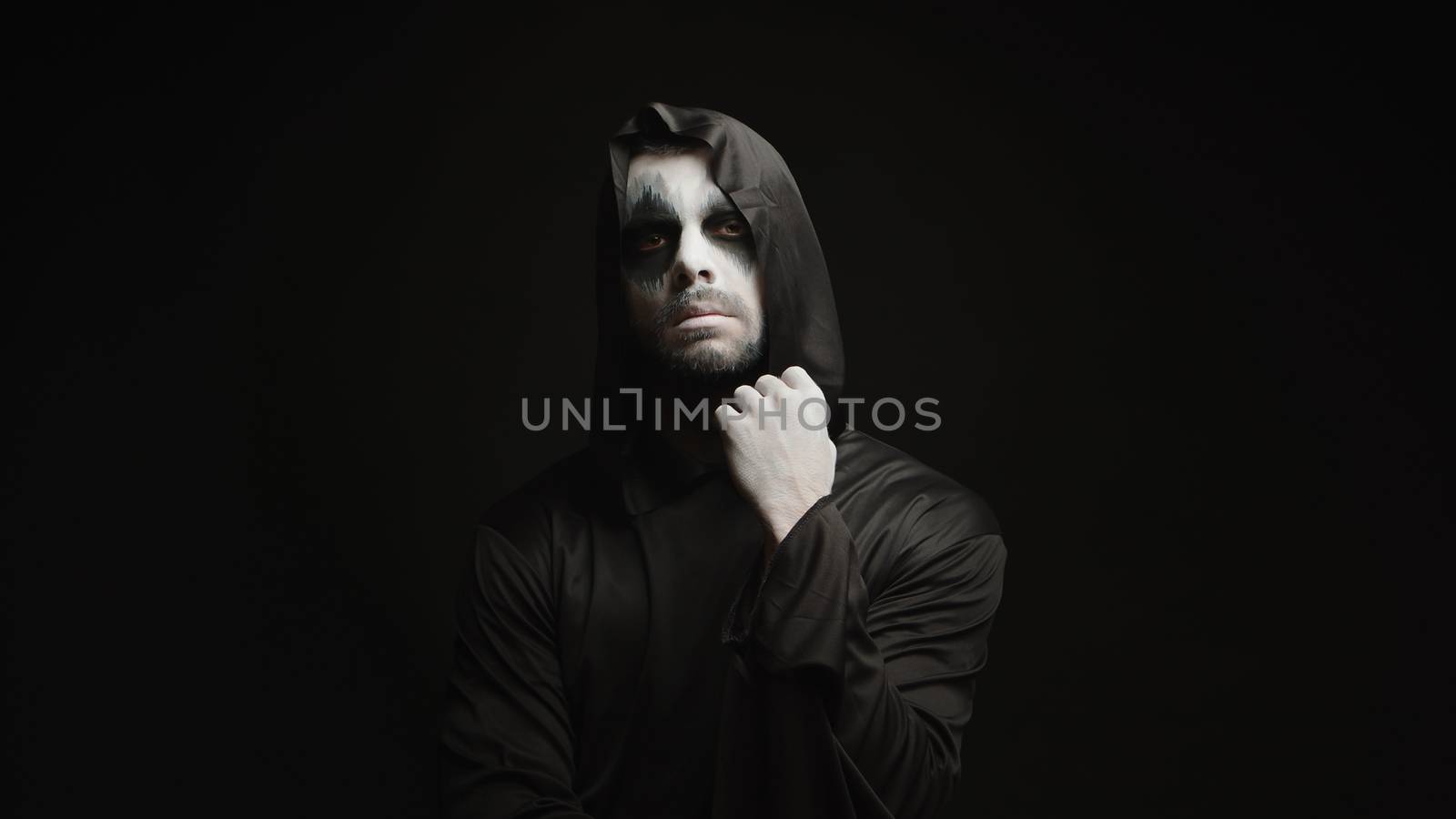 Thoughtful scary grim reaper over black background. Halloween demon.