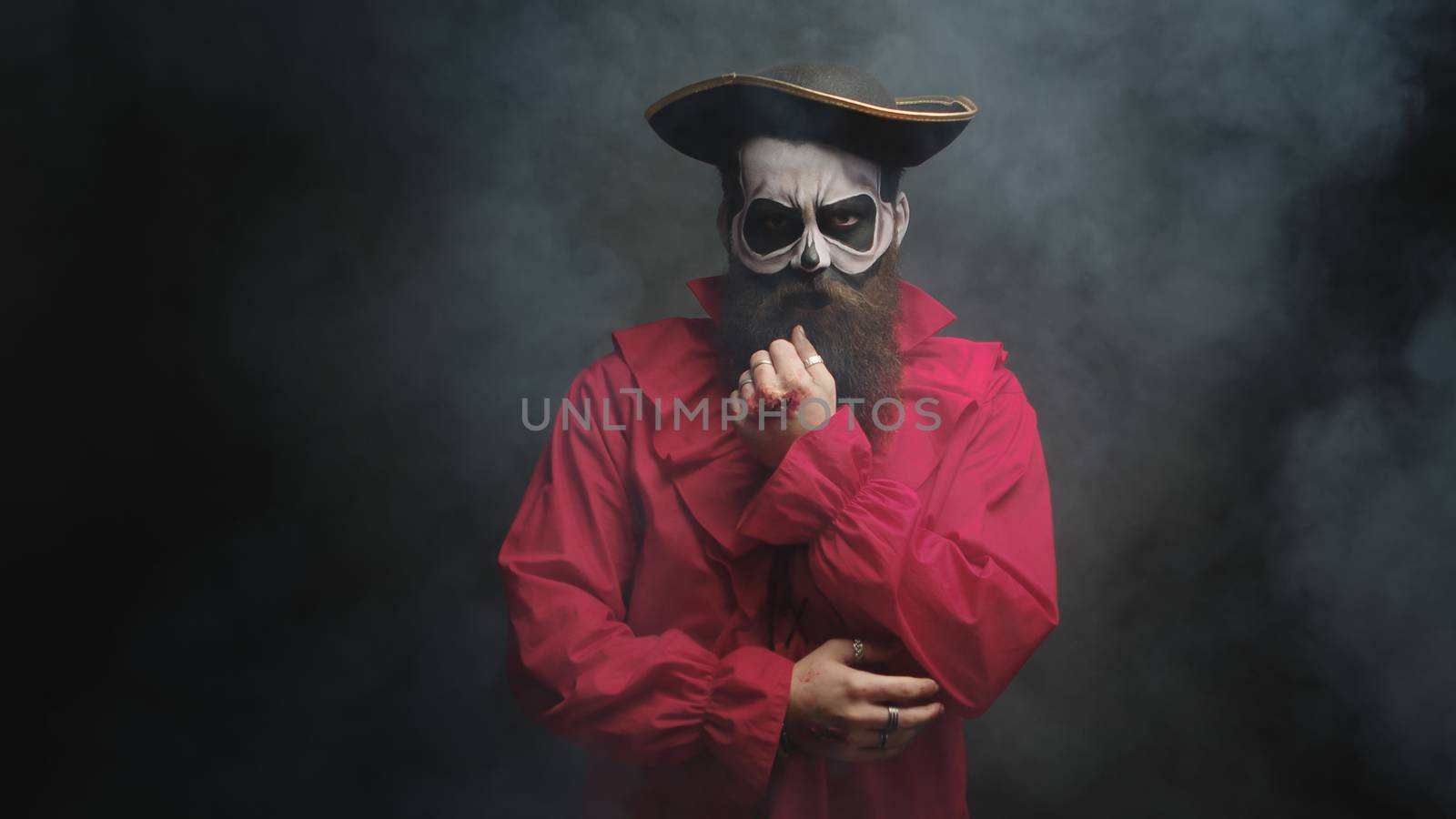 Man with long beard dressed up like a pirate for halloween over a black background with smoke coming out.