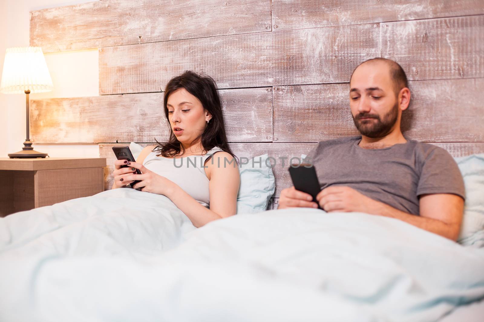 Couple wearing pajamas and using their phones before bedtime.