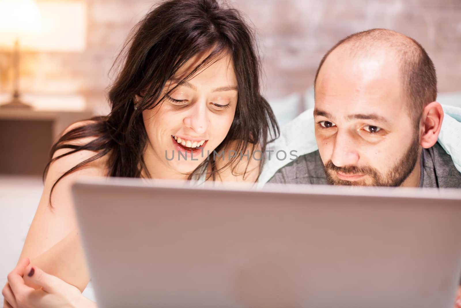 Close up of married couple in pajamas using tablet computer.