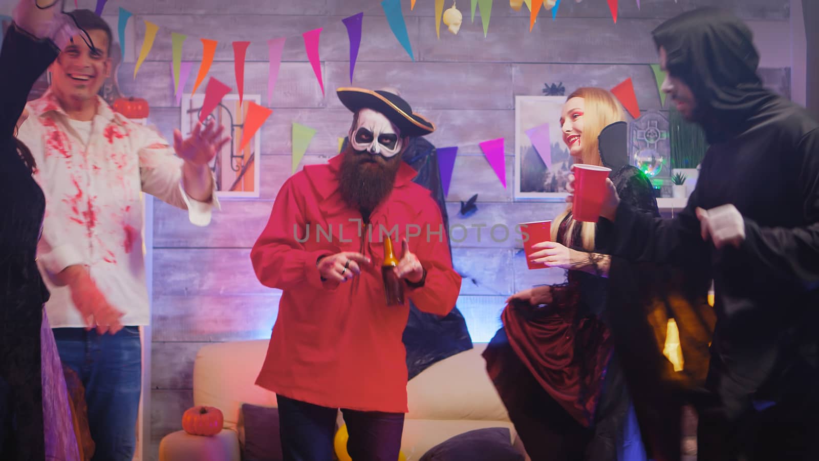 Man dressed up like a pirate dancing with people dressed up like different monsters at halloween party.