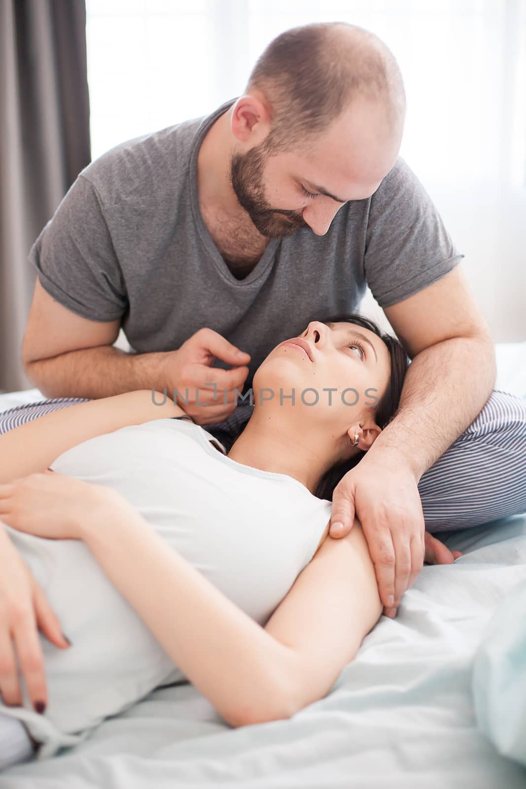 Bearded husband in pajamas looking at his wife after waking up.