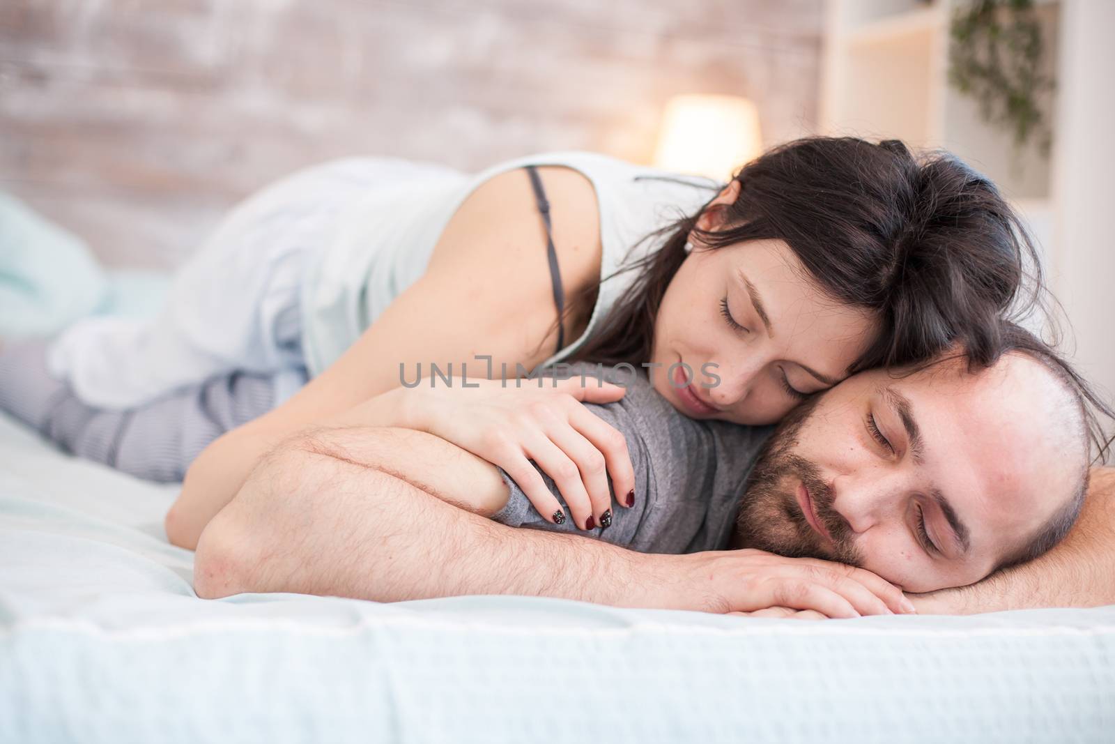 Beautiful caucasian woman in pajamas sleeping on boyfriend back in the morning.