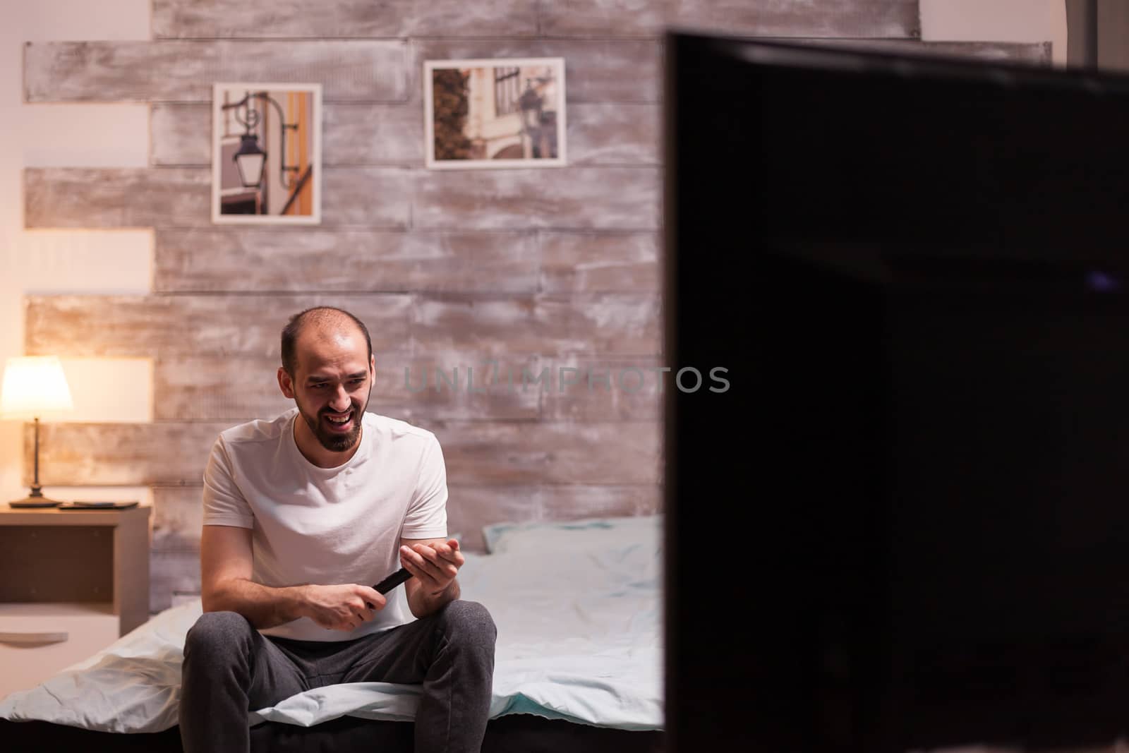 Amused man in front of tv by DCStudio