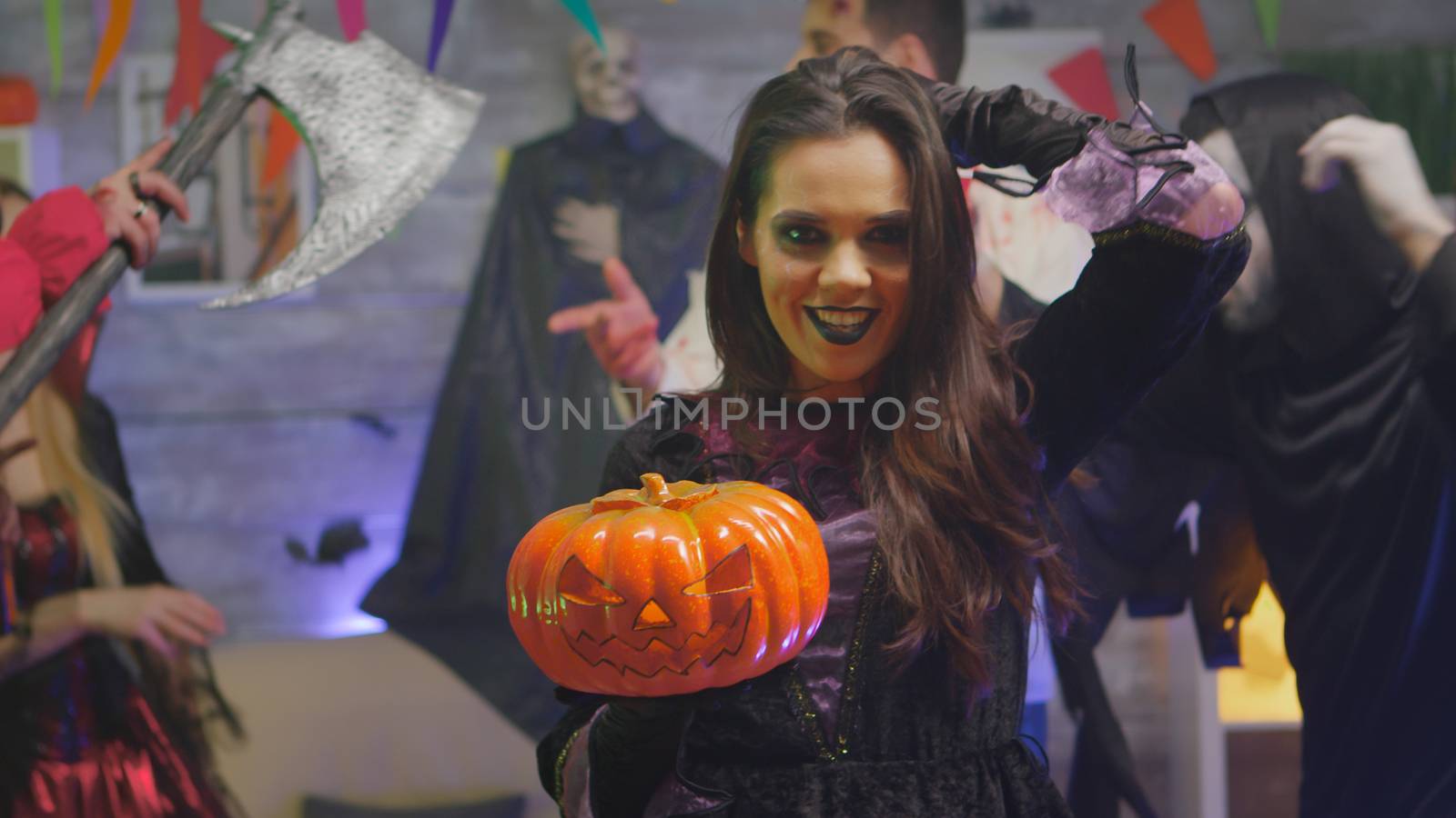 Spooky witch celebrating halloween with her friends dressed up like different scary monsters in decorated room
