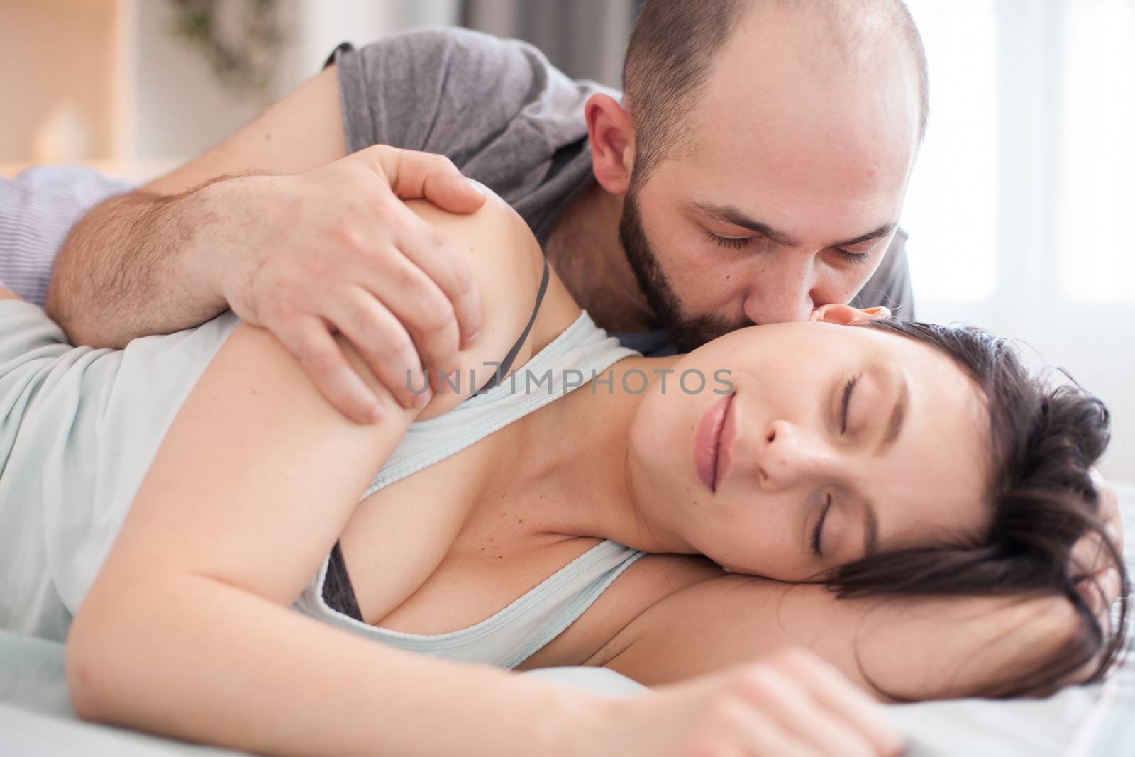 Husband in the morning kissing his wife cheek by DCStudio