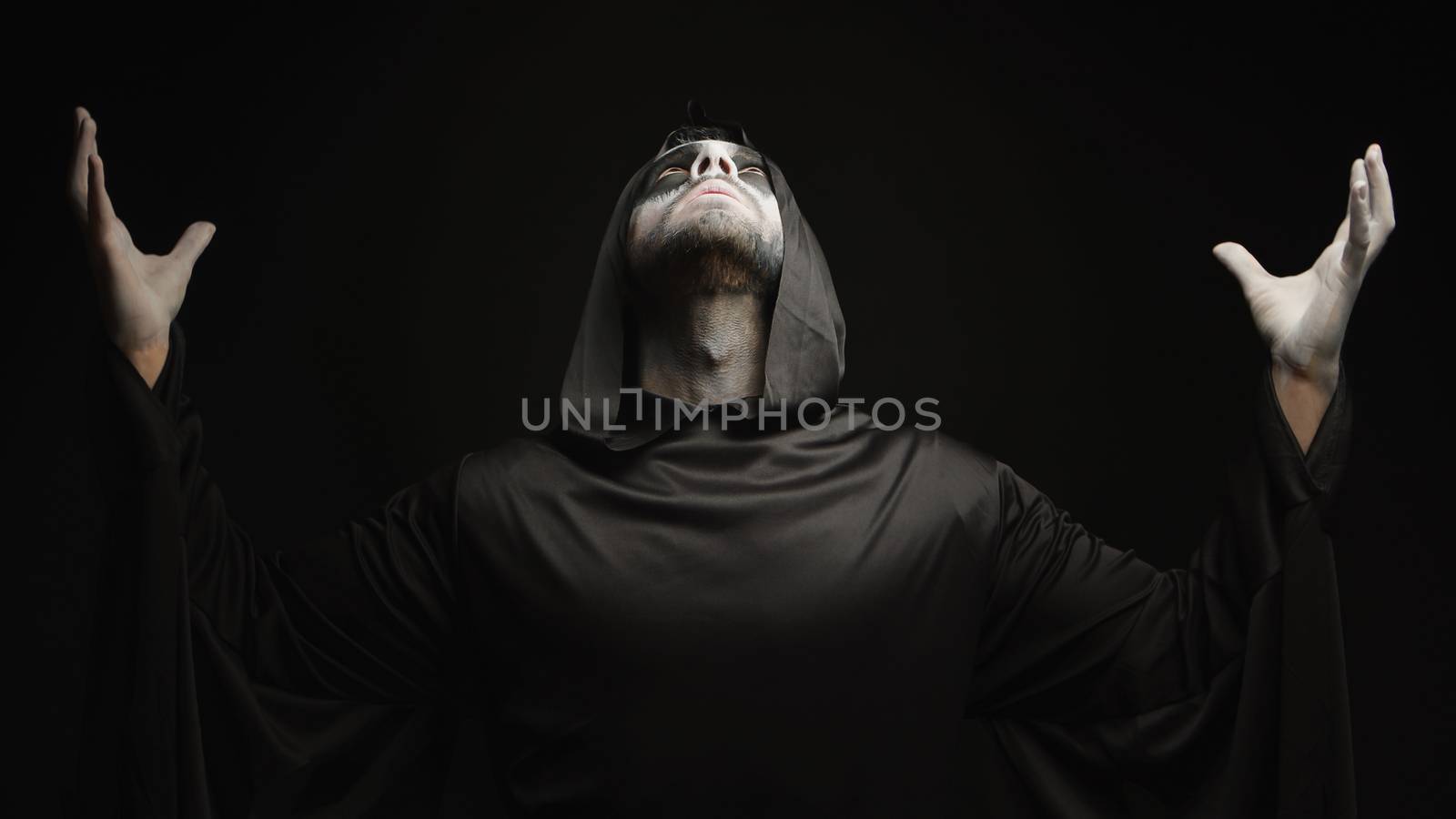 Young man dressed up as angel of darkness for halloween over black background.
