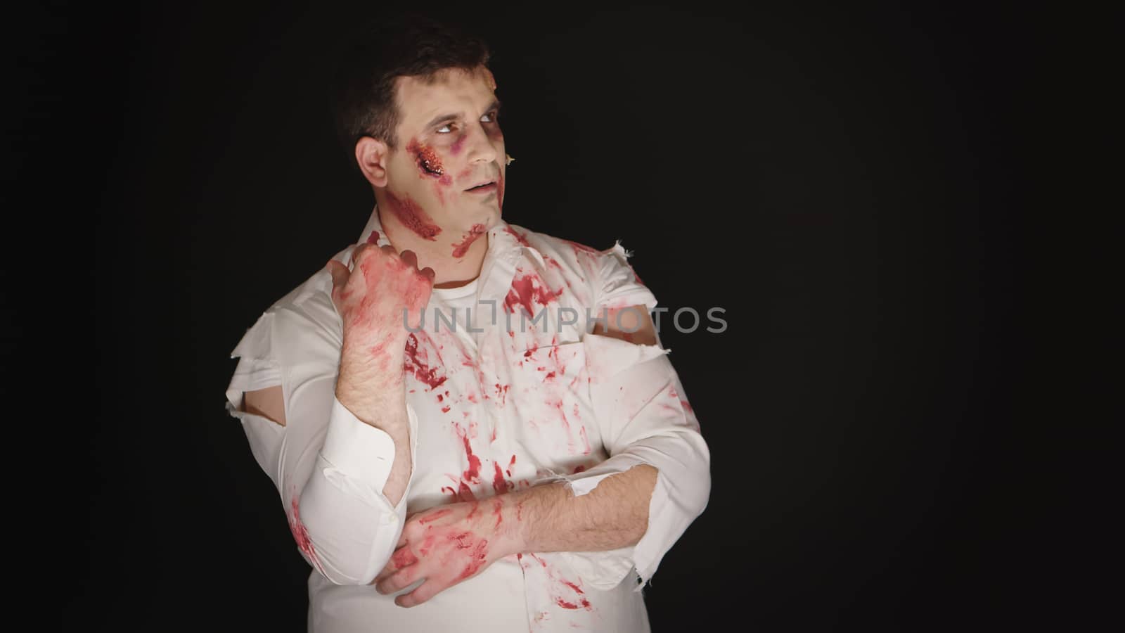 Young man with blood on his face dressed up like a zombie for halloween.