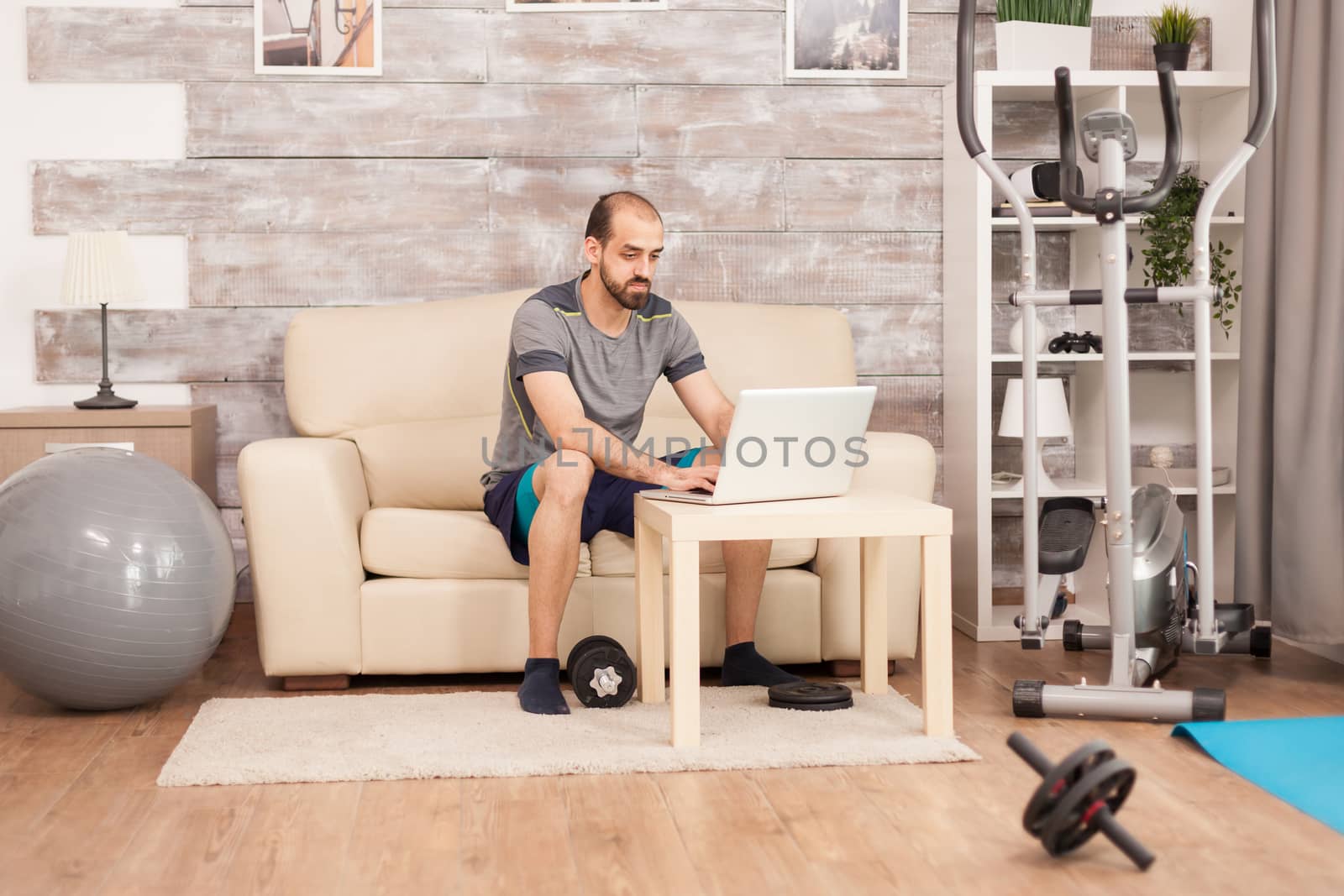 Athletic man in home searching online training by DCStudio