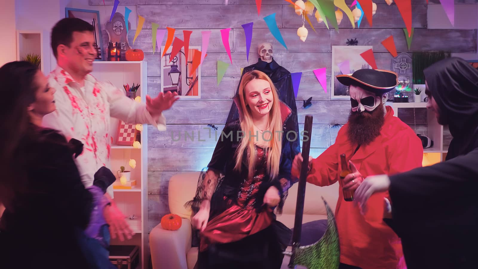 Bearded pirate with axe and his friends dancing at halloween celebration in decorated room