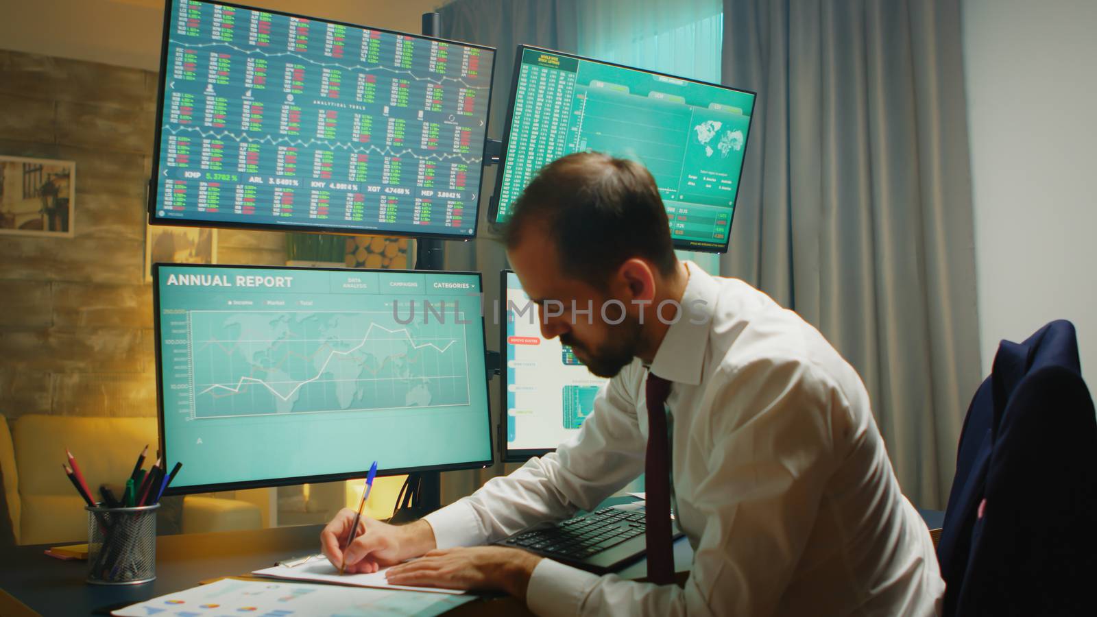Stock market trader pointing at monitor computer and taking notes. Financial crash.