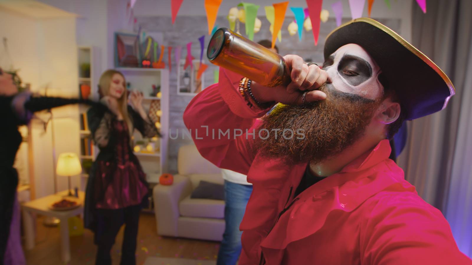 Pov of bearded pirate celebrating halloween with his friends inviting everybody to the party while other scary characters are dancing in the background in decorated house