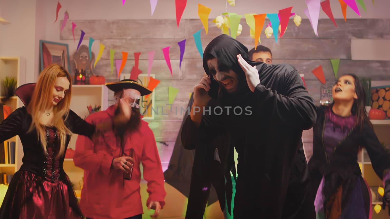 Man dressed up like a grim reaper at halloween party talking on the phone.