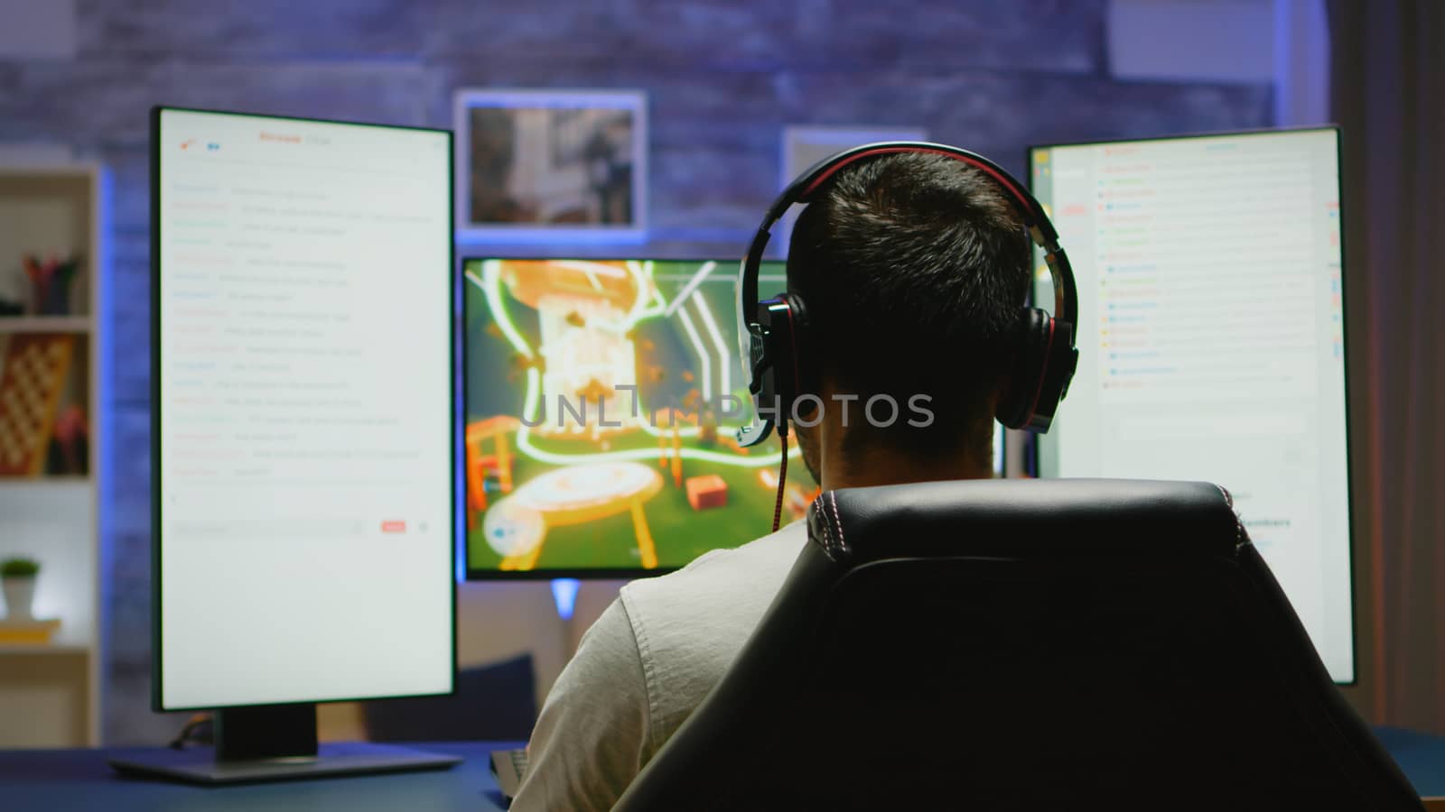 Back view of young man with hands raised celebrating victory at online shooter game.