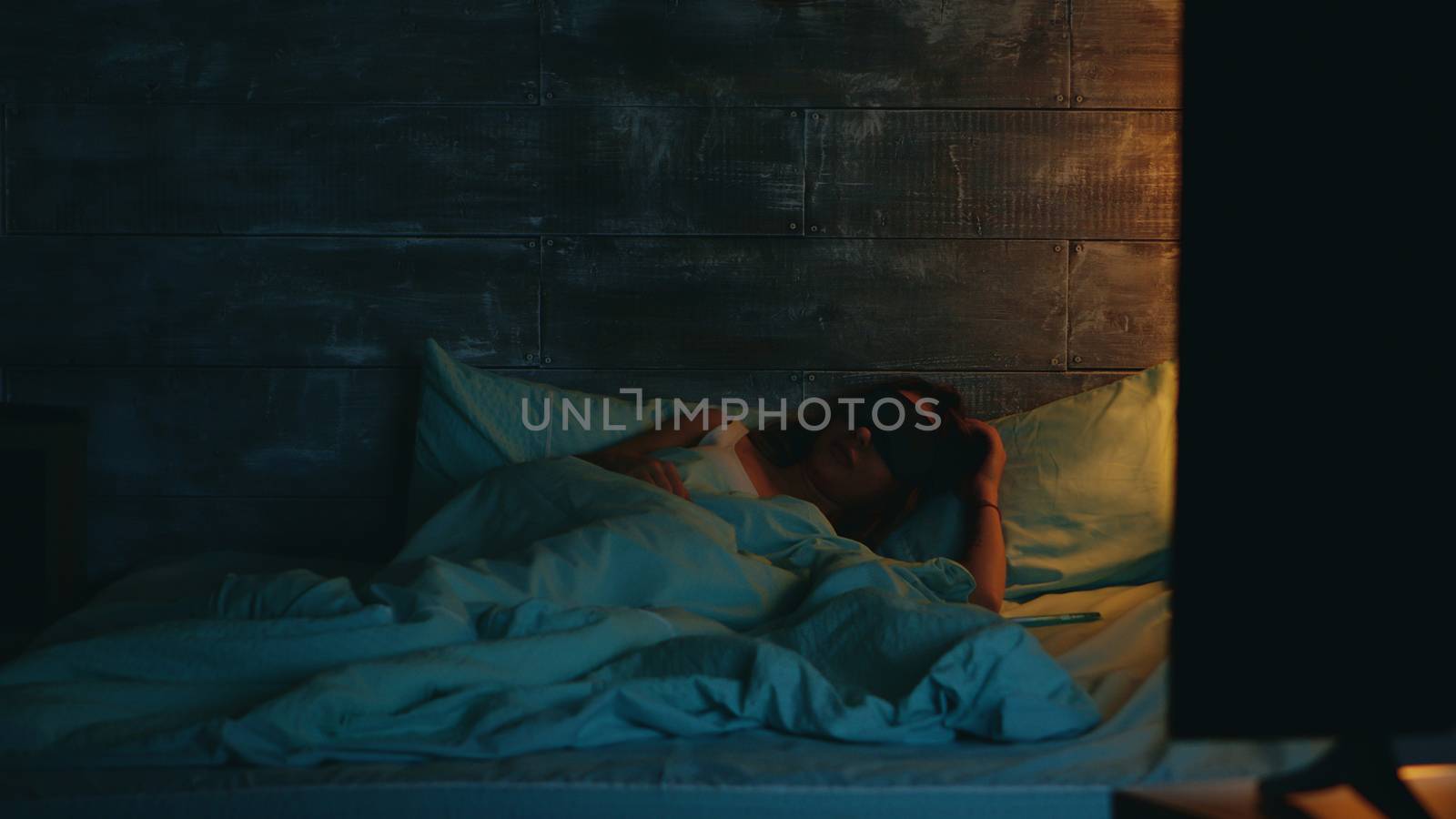 Woman in pajamas turning the light off from phone app by DCStudio